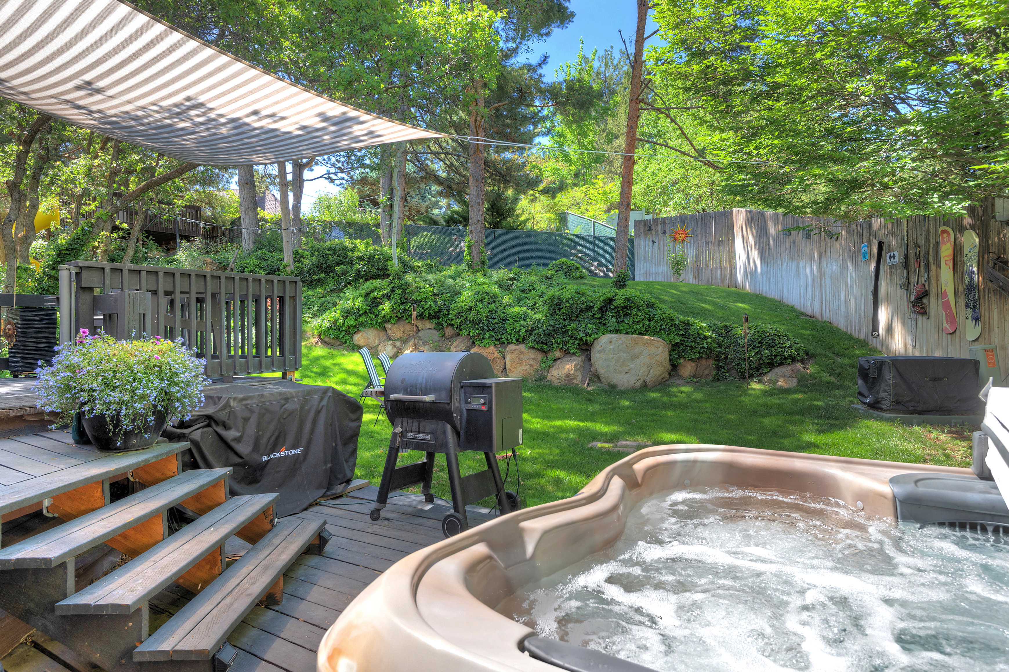 Expansive backyard featuring a built-in hot tub, multi-level wood deck, and a shaded pergola