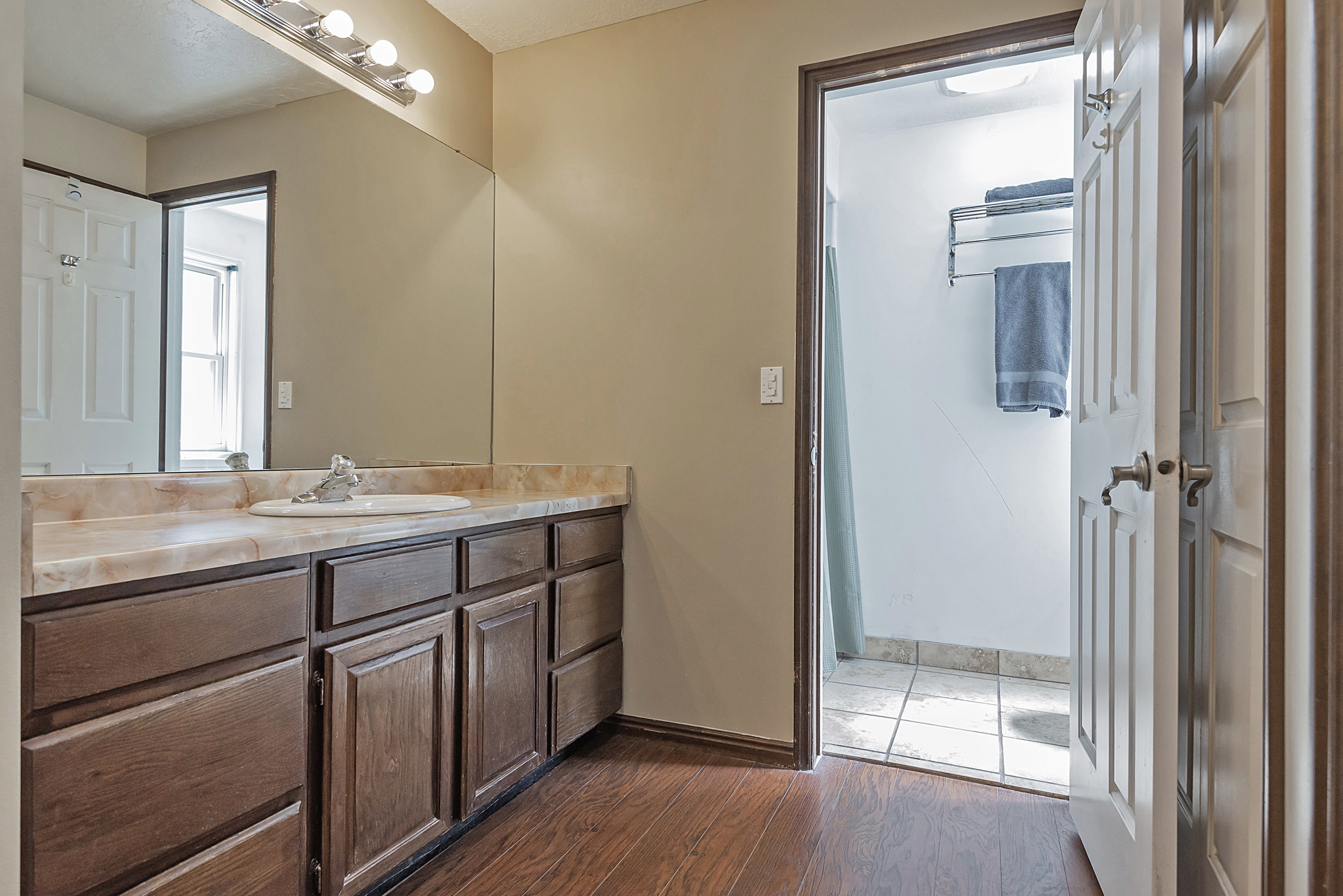 Vanity area featuring a wood-finish cabinet with multiple storage drawers and doors, a beige countertop with an integrated sink, and an overhead vanity light fixture