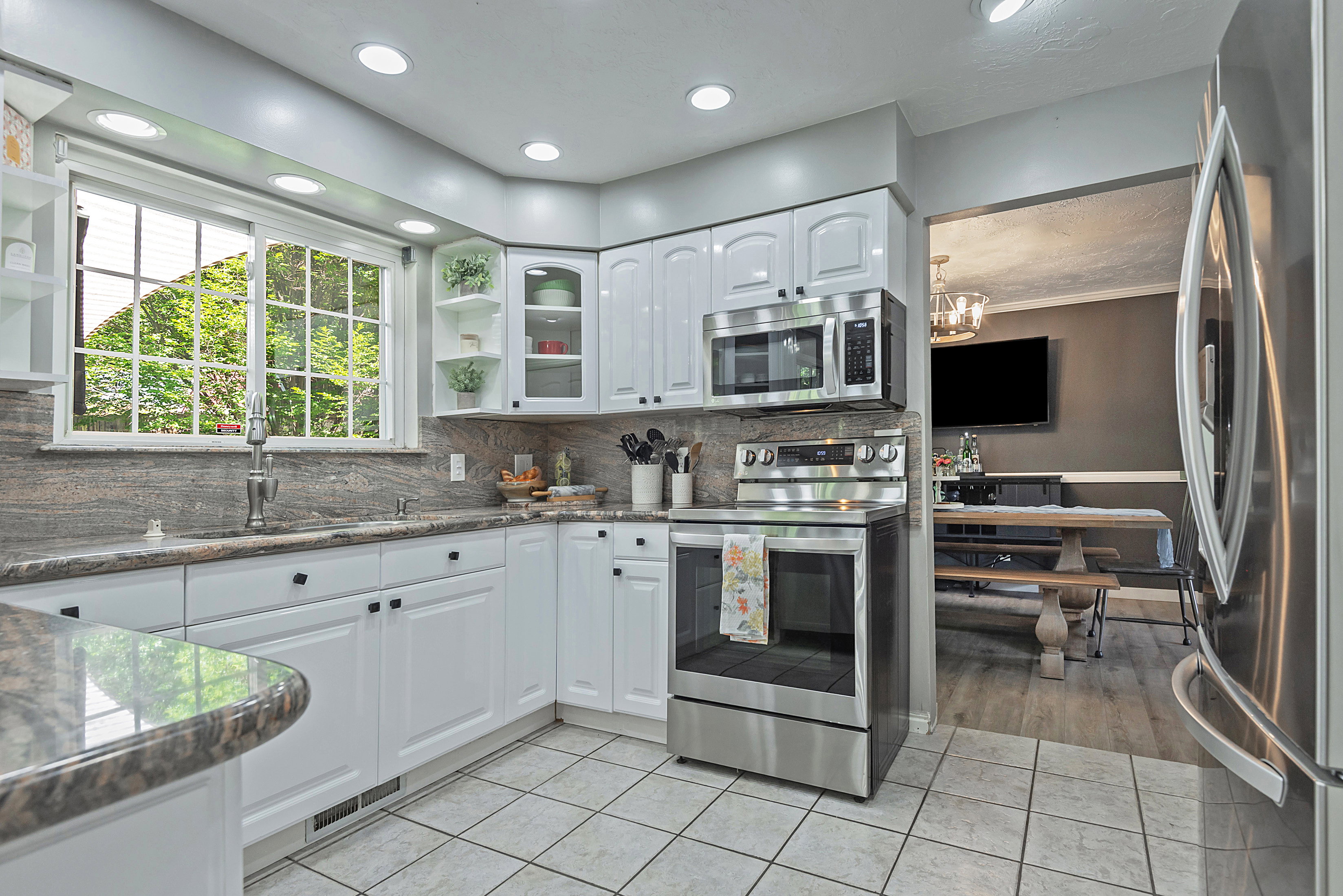 Kitchen featuring white cabinetry, stainless steel appliances, granite countertops, and tile flooring