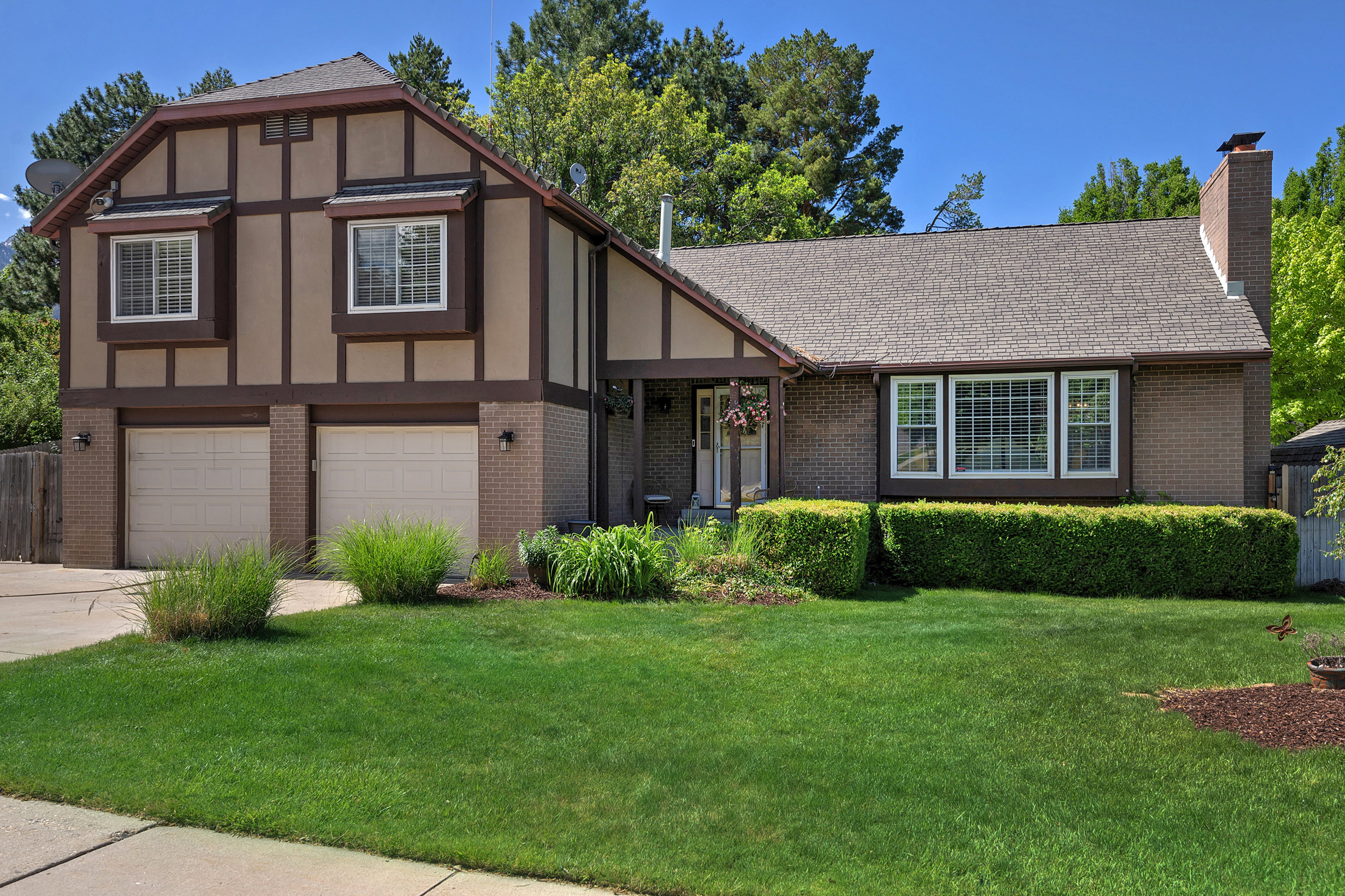 Tudor-style exterior featuring a two-car garage, brick accents, and a prominent chimney