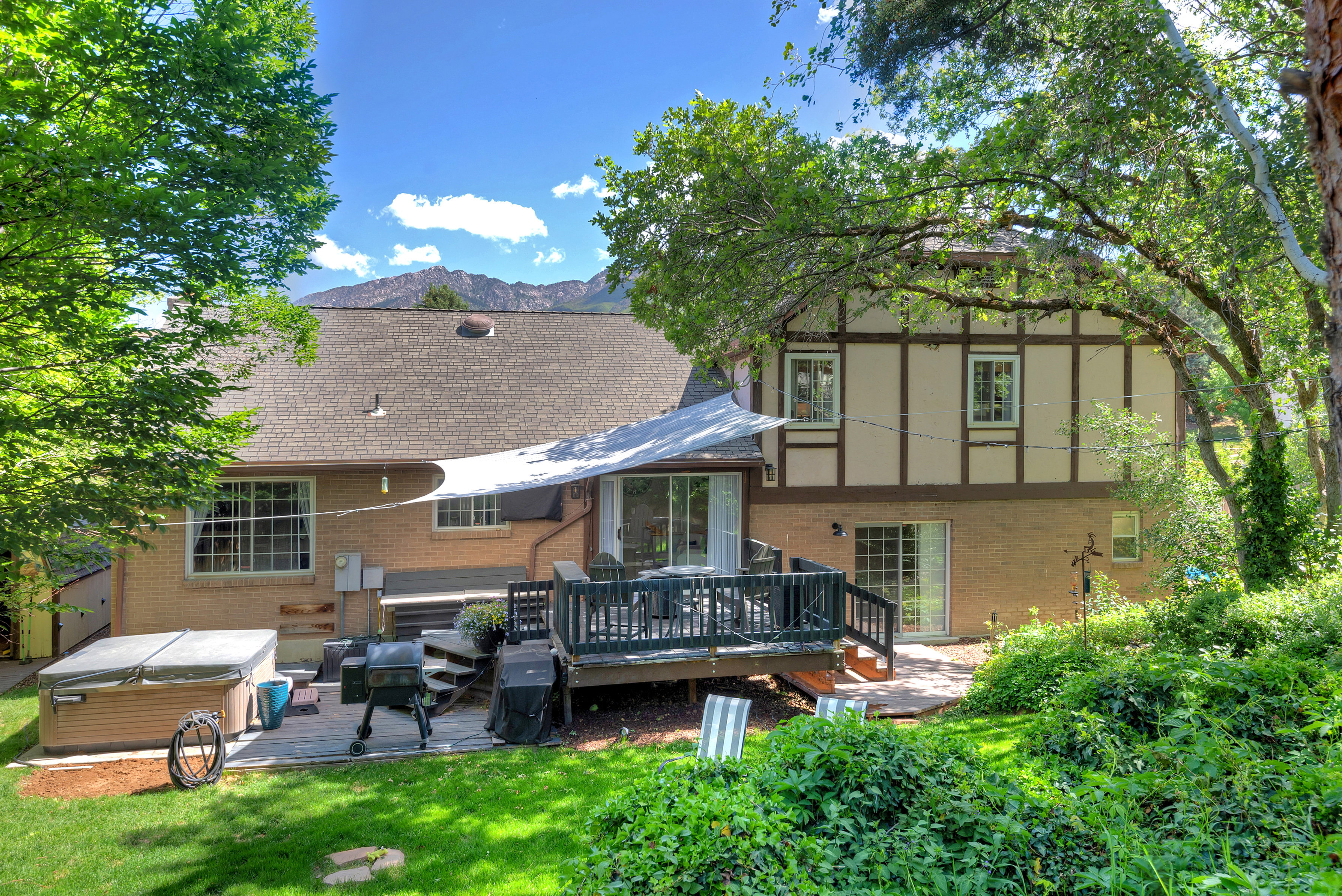 Expansive backyard featuring a multi-level deck, mature trees, and mountain backdrop