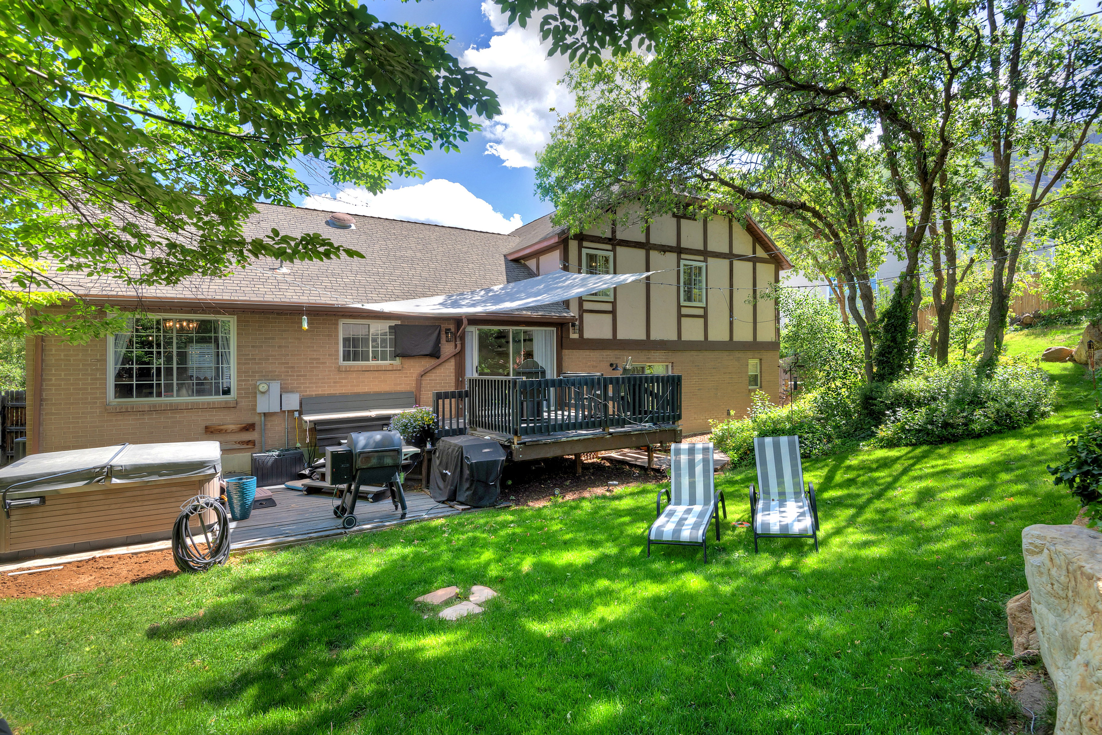 Expansive backyard featuring a manicured lawn, multi-level deck, and mature trees