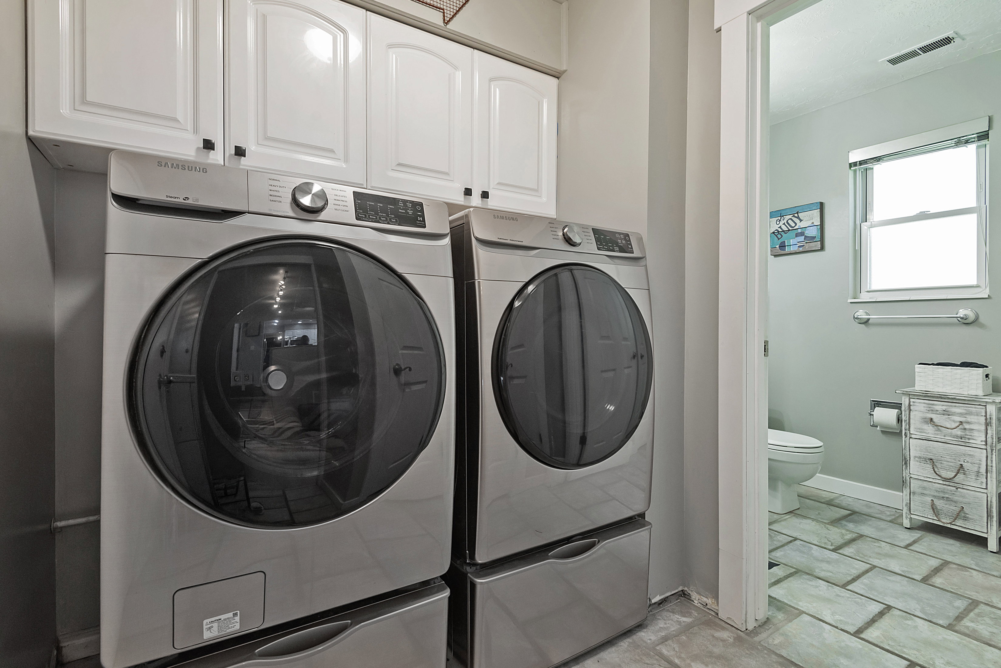 Laundry area with white upper cabinetry and a side-by-side washer and dryer