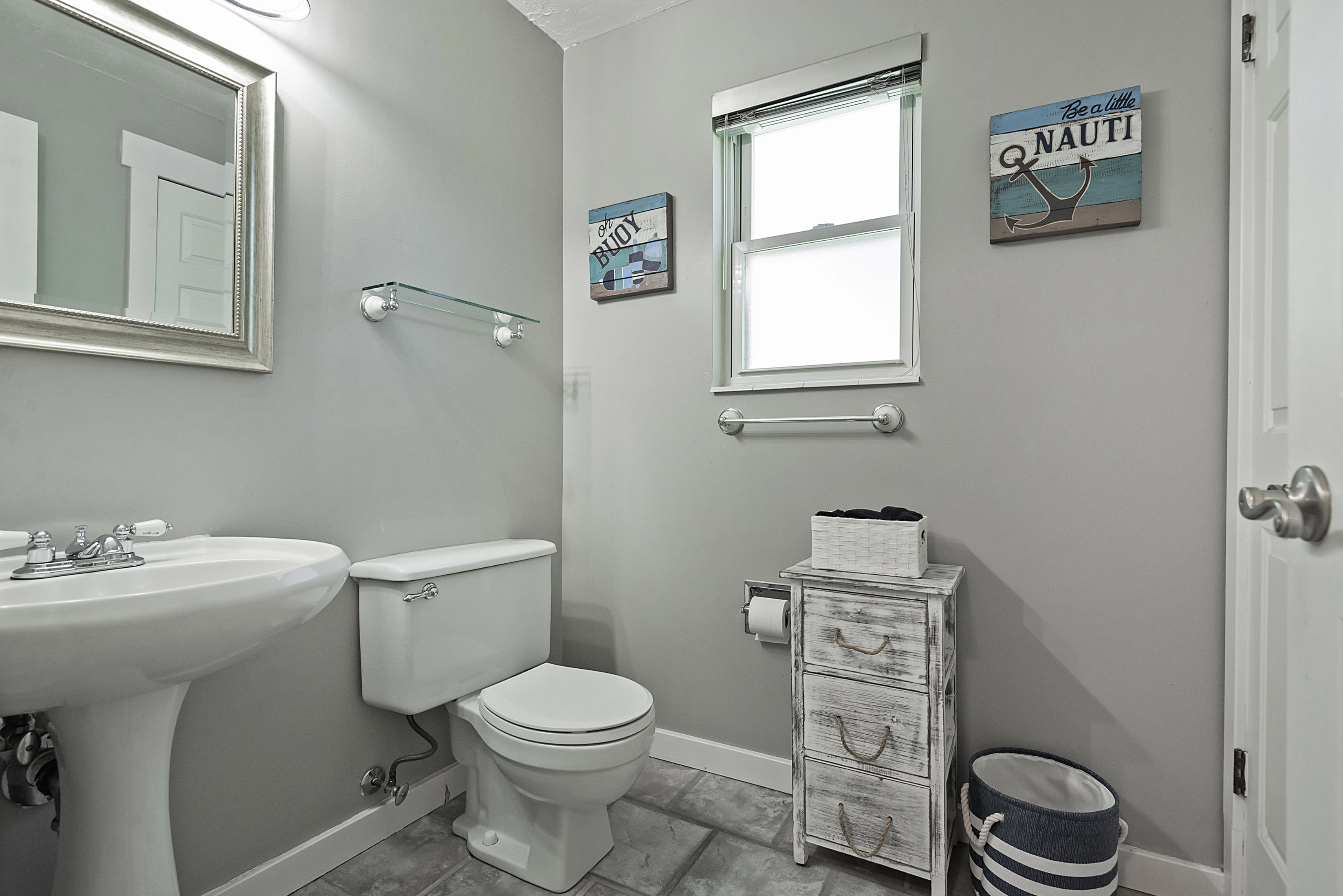 Bathroom featuring a pedestal sink, white toilet, and a window with blinds