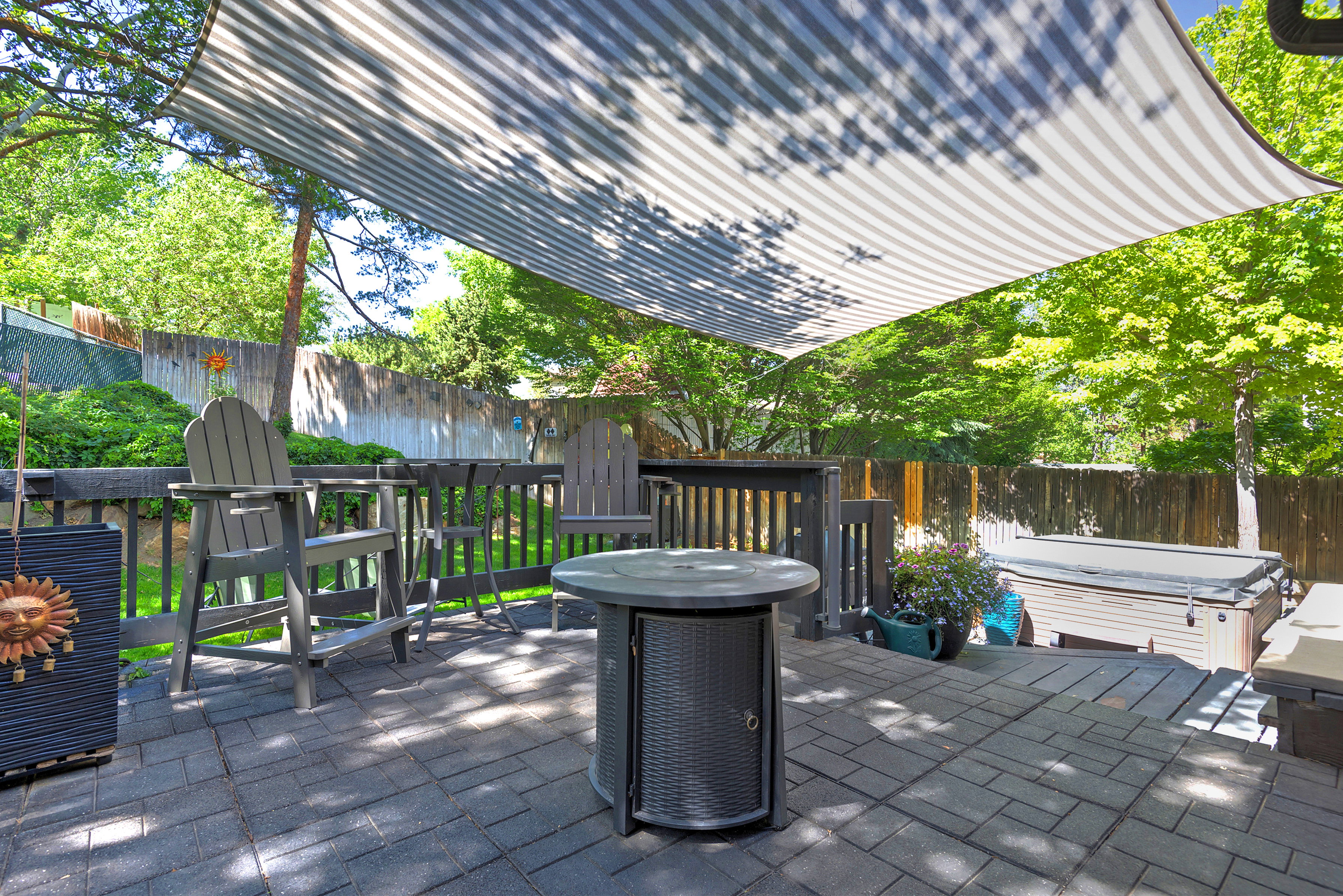 Outdoor living area featuring a striped shade sail over a stone paver patio