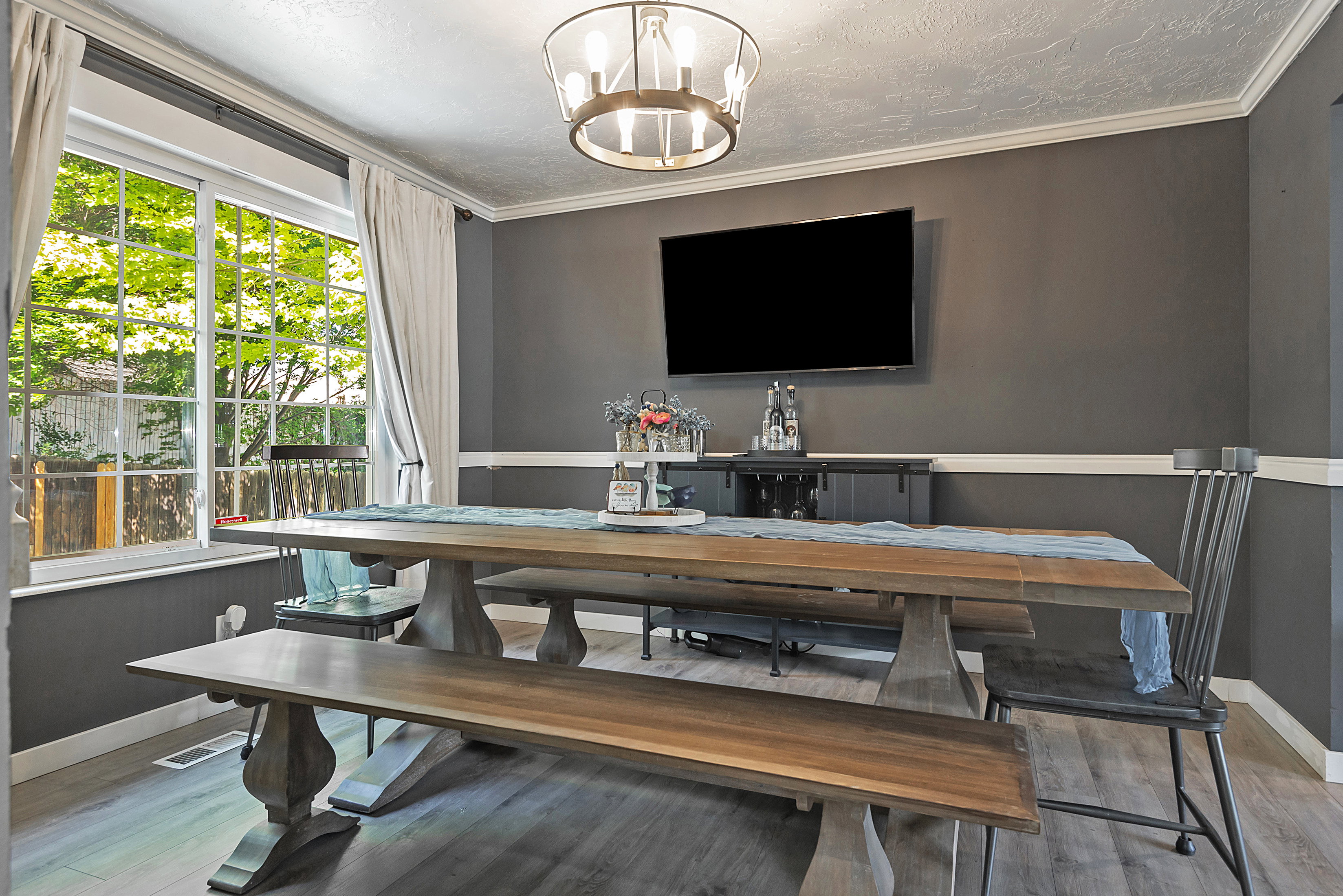 Interior space featuring wood-finish flooring, a contemporary chandelier, and a large window with white trim