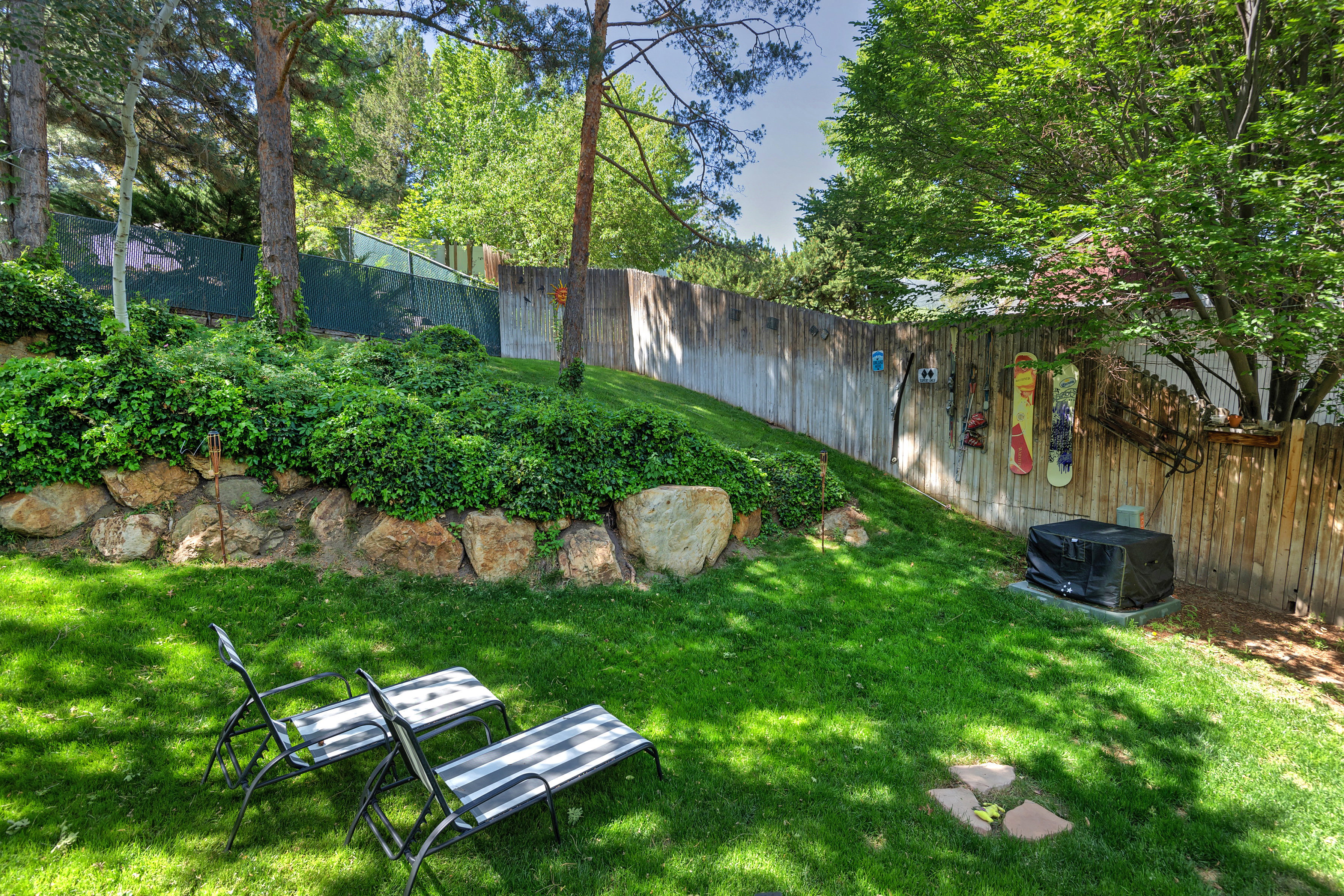 Expansive rear yard featuring a manicured lawn, established landscaping, and mature trees