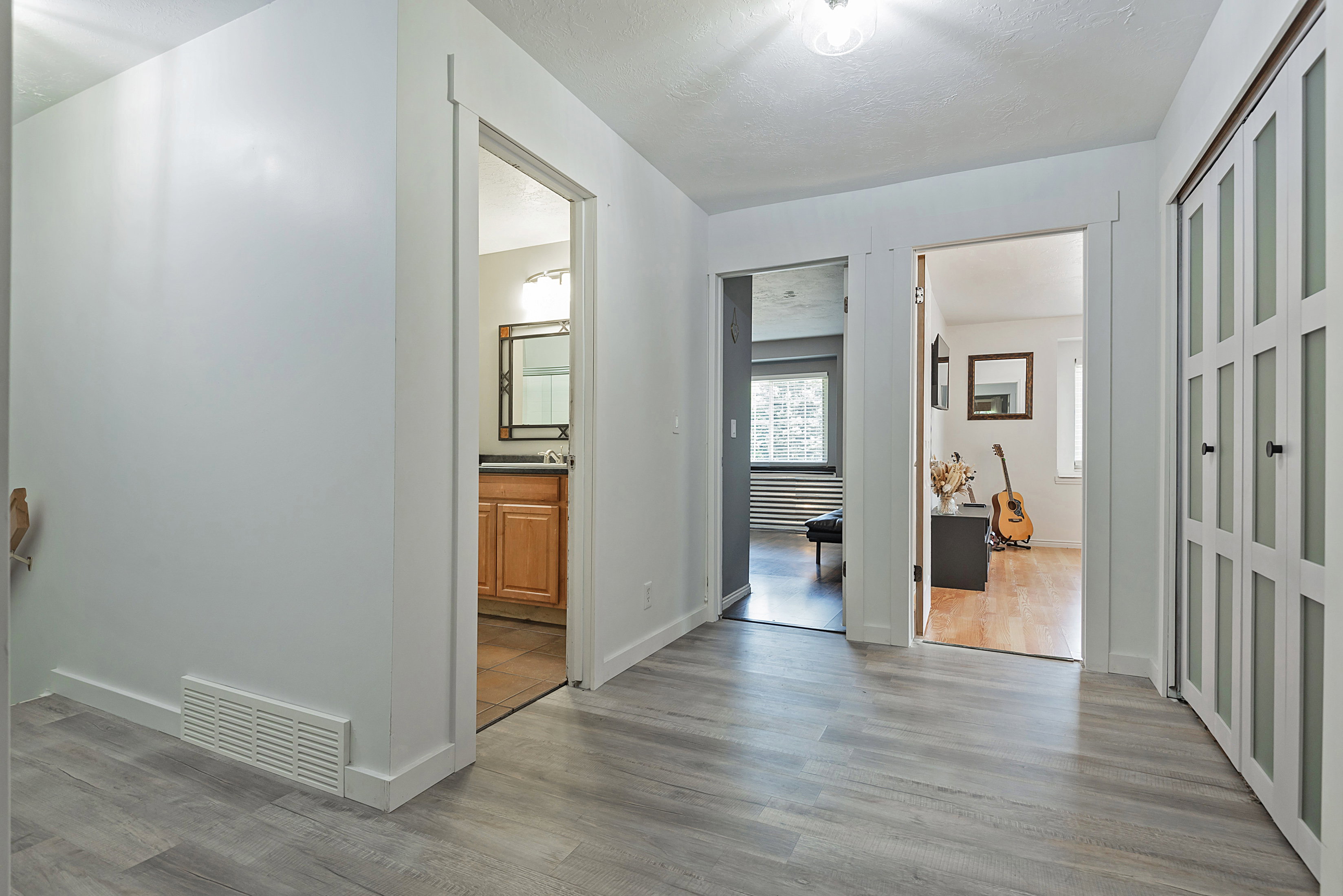 Contemporary hallway with wood-finish flooring, white trim, and a ceiling light fixture