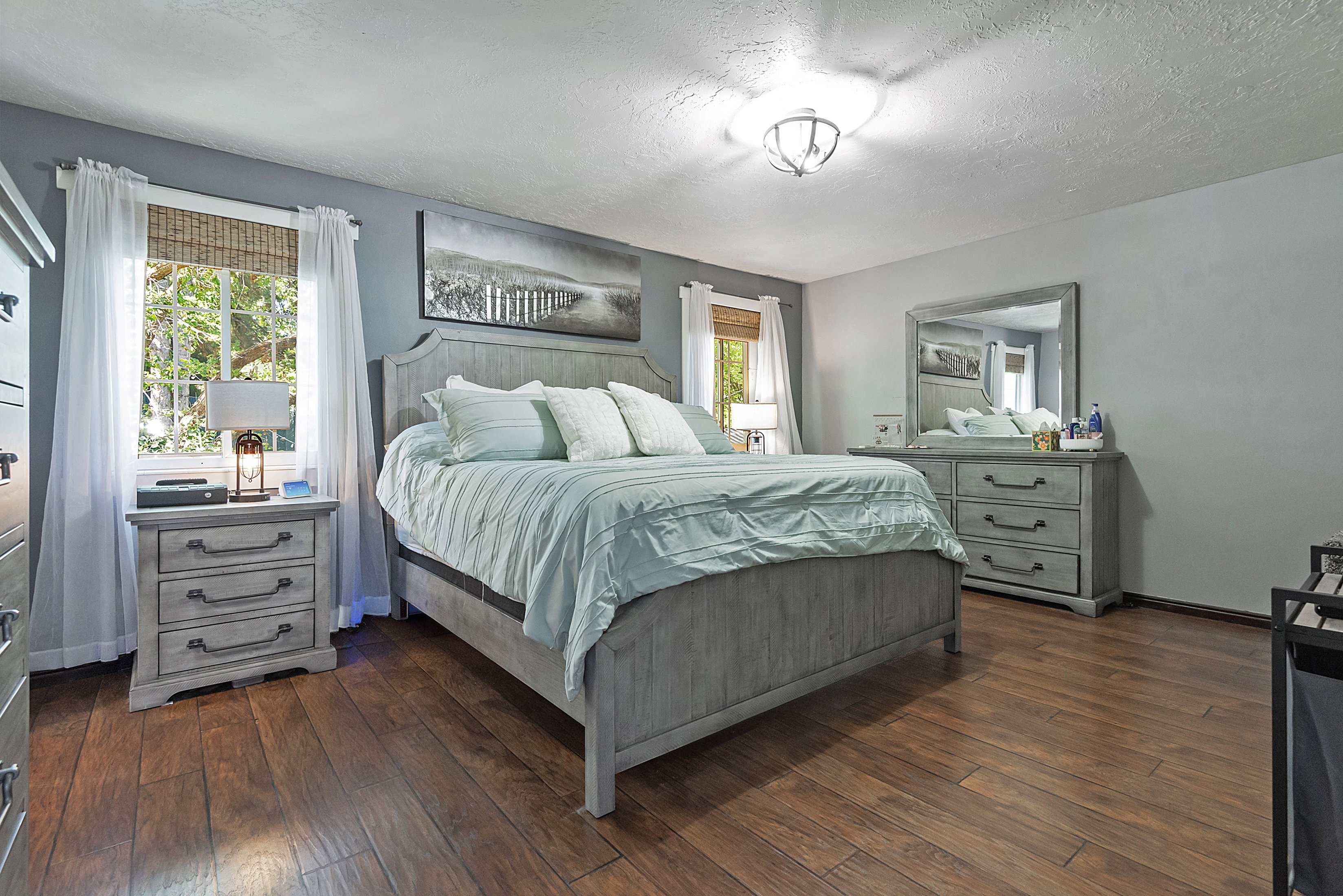 Spacious room featuring wood-finish flooring, light gray walls, and a ceiling-mounted light fixture