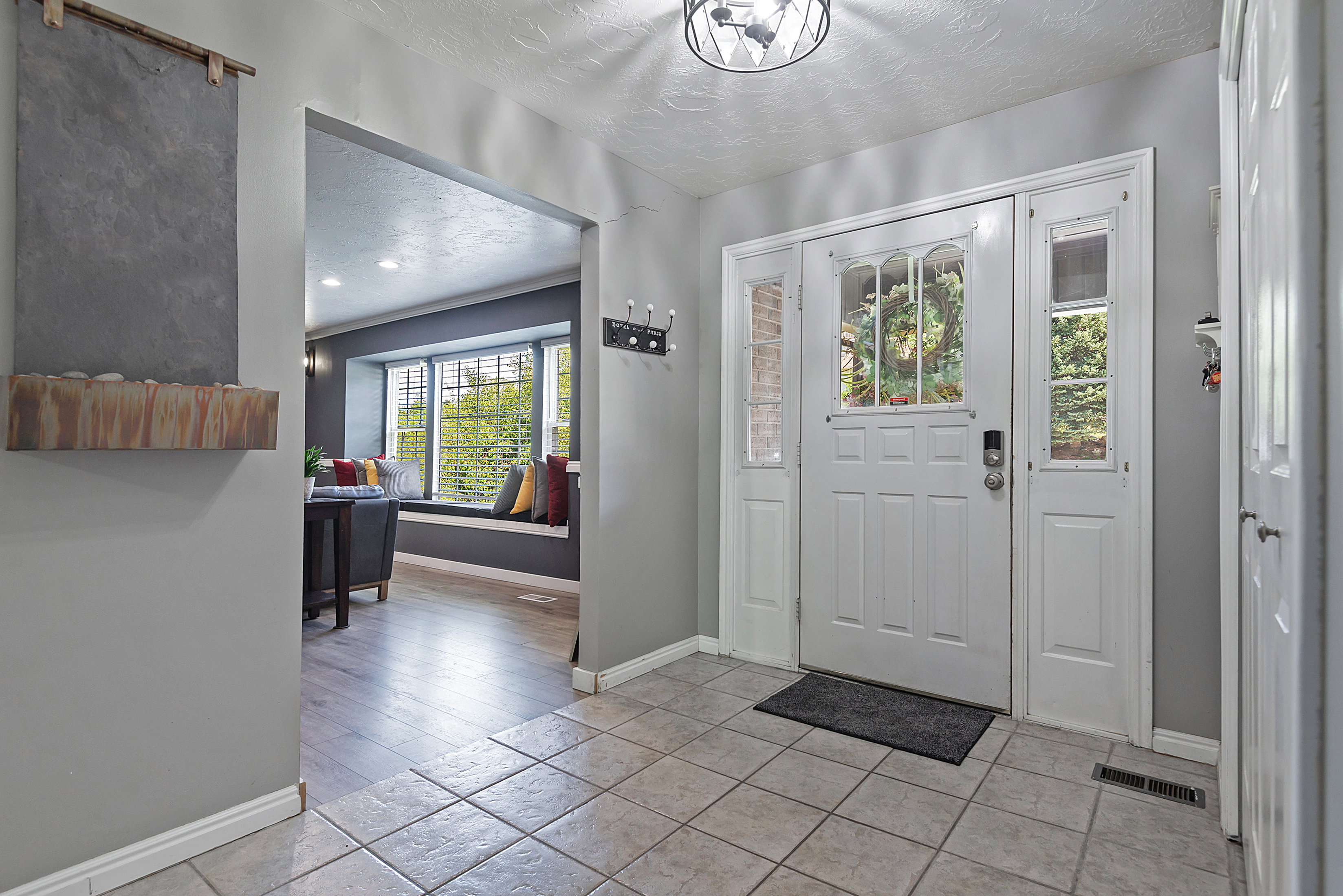 Entryway featuring ceramic tile flooring, a white paneled front door with decorative glass, and sidelight windows