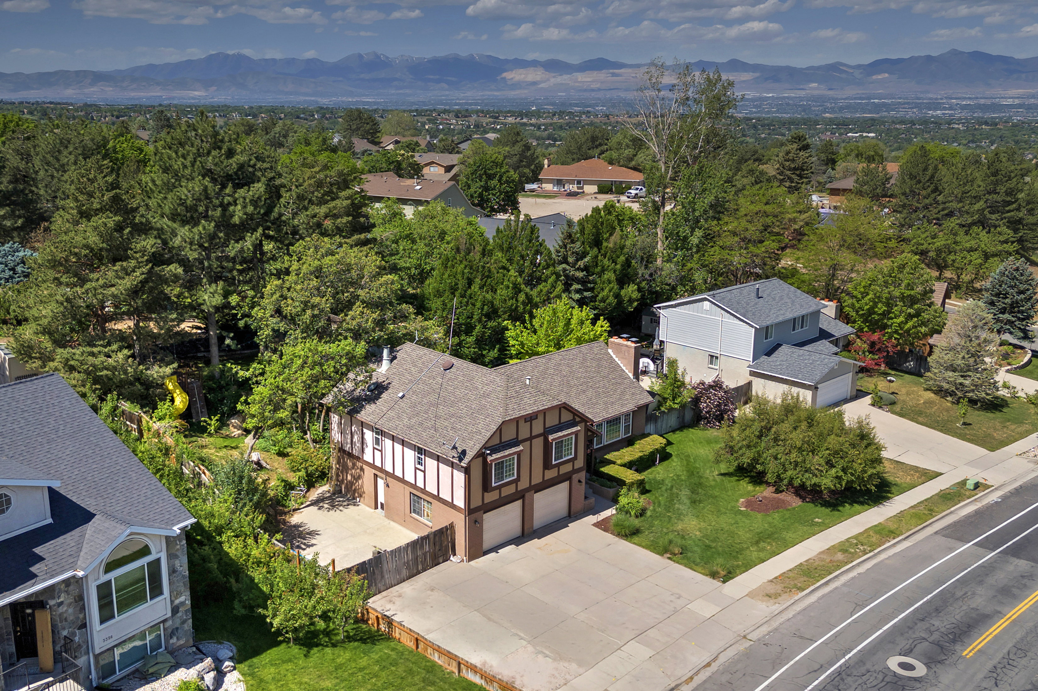 Tudor-style home featuring a two-car garage, pitched roofline, and established landscaping