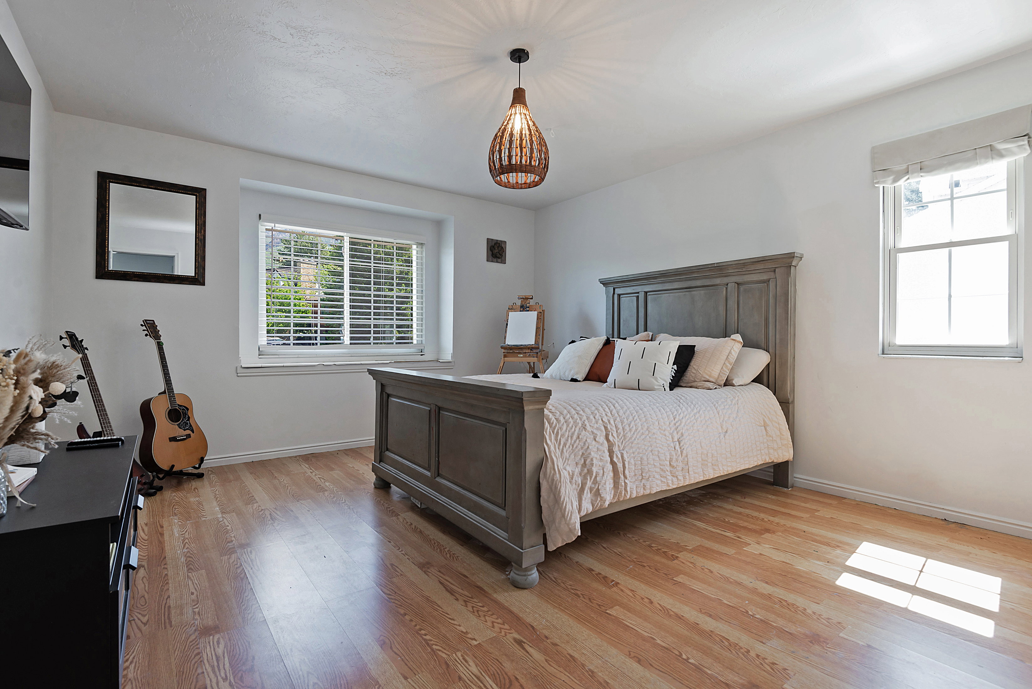 Spacious room featuring wood-finish flooring, white walls, and a ceiling-mounted light fixture