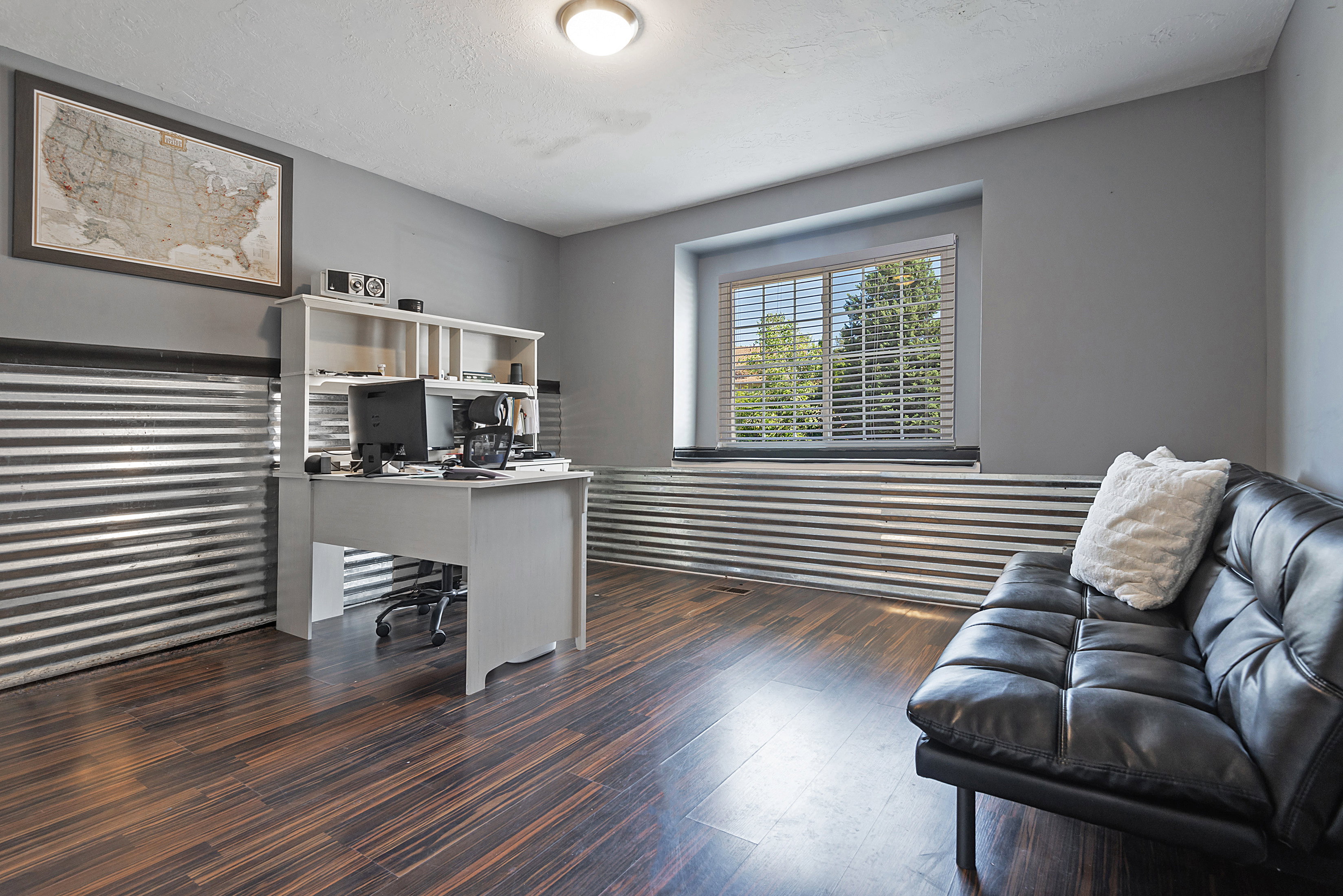 Room featuring wood-finish flooring, corrugated metal wainscoting, and a window with blinds