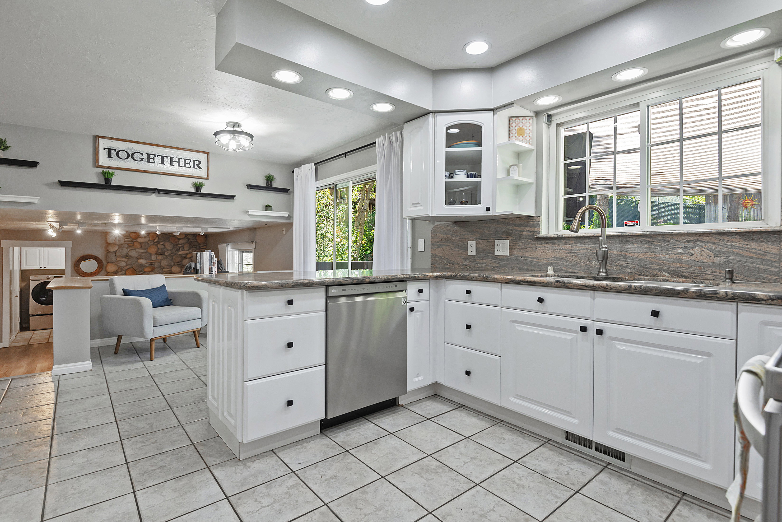 Kitchen featuring white cabinetry with black hardware, granite countertops, stainless steel dishwasher, recessed lighting, and tile flooring