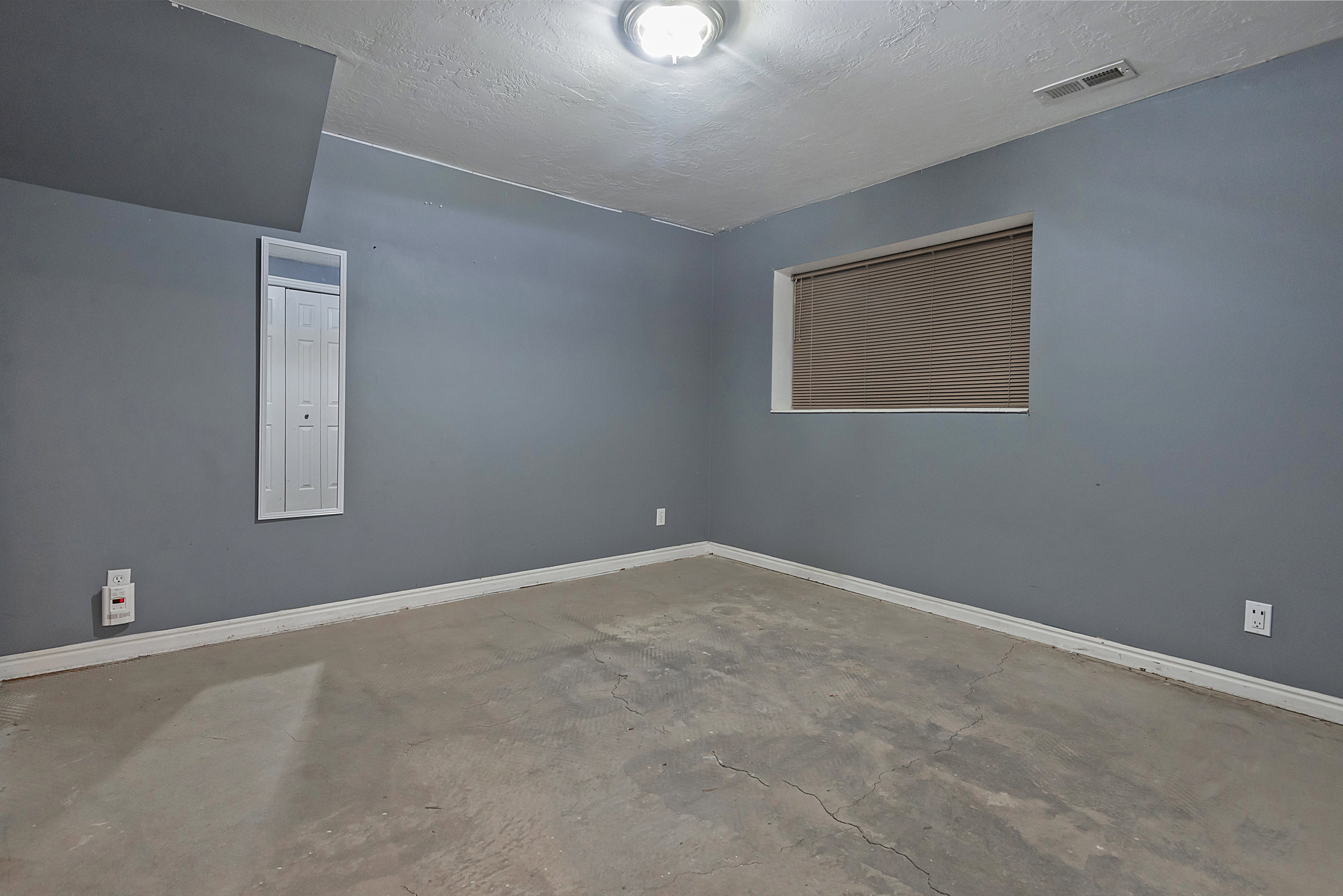 Room featuring textured blue-gray walls, white trim, and a concrete floor
