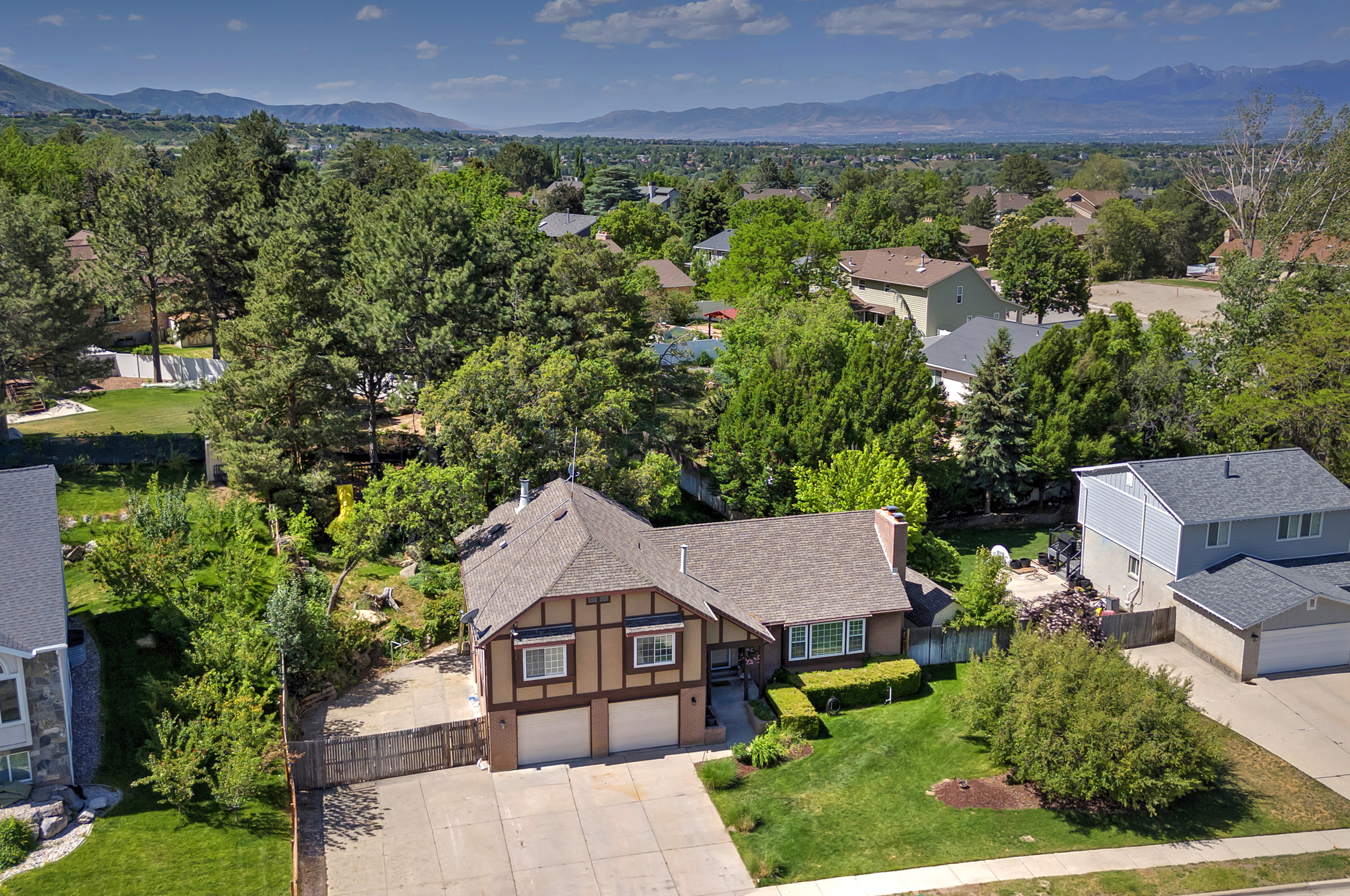 Tudor-style residence featuring a two-car garage, extensive driveway, and a fenced backyard