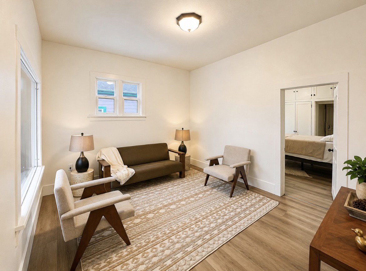 Unit 1 living room. Bright interior space featuring light-toned walls and wood-finish flooring