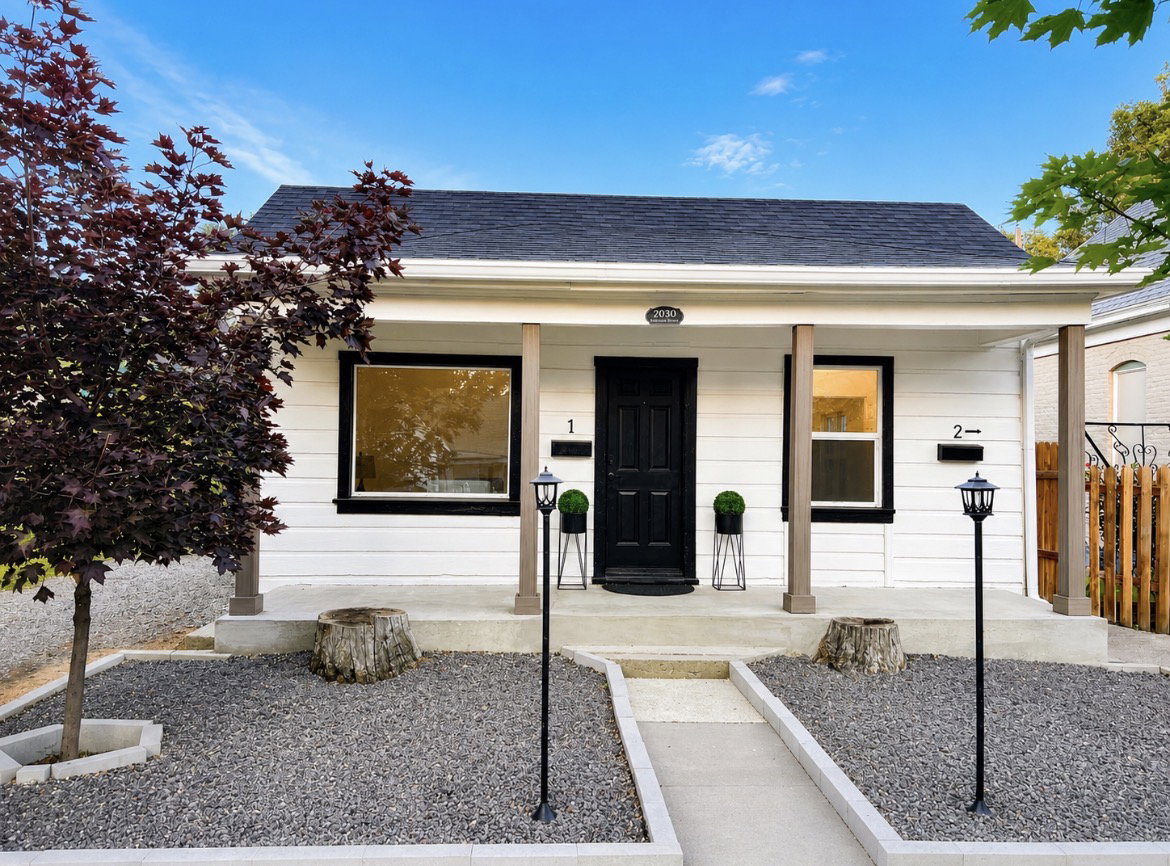 White siding exterior with a dark shingle roof and a covered front porch supported by brown columns