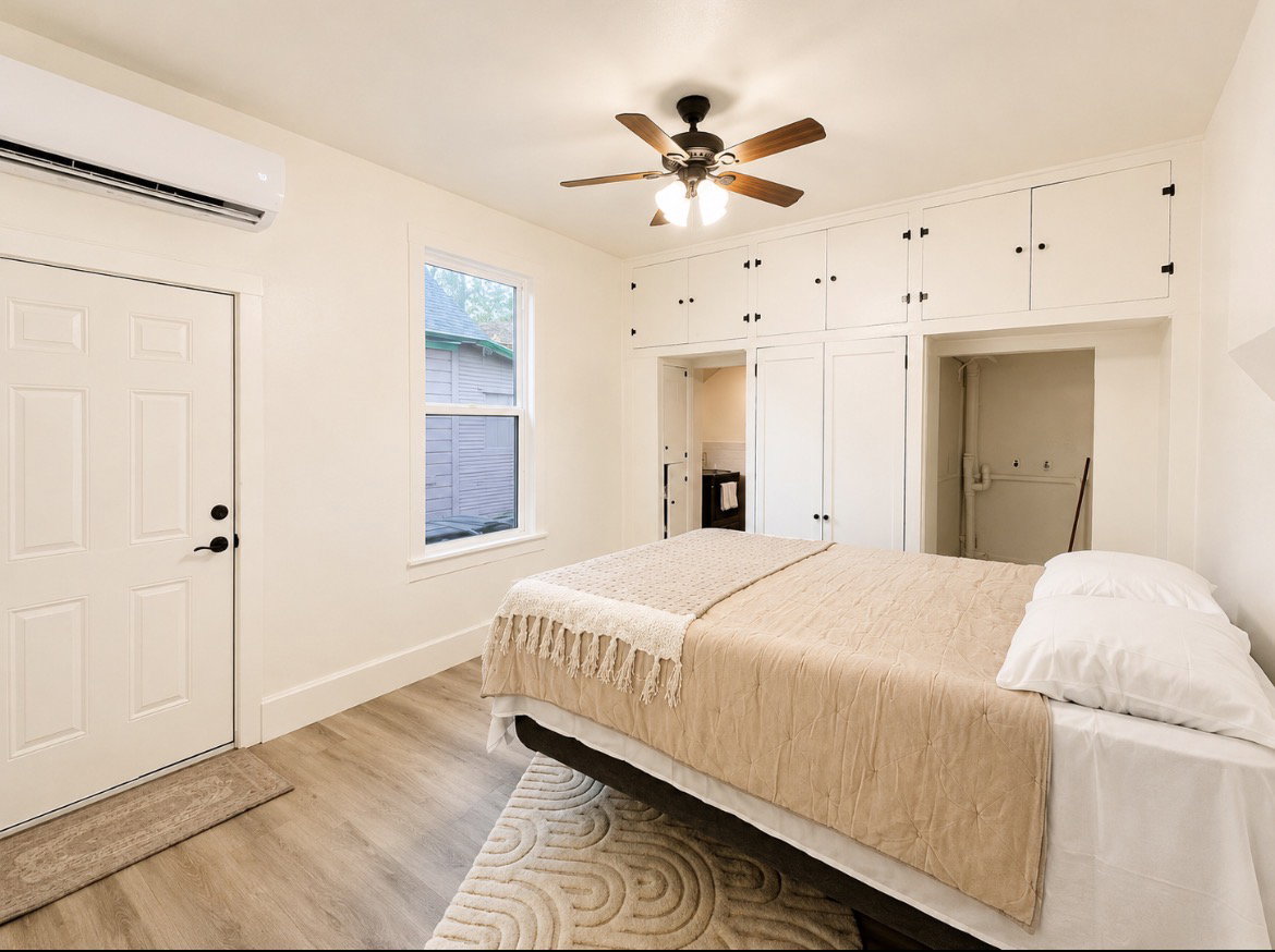 Unit 1 bedroom. Room featuring wood-finish flooring, built-in cabinetry, a ceiling fan with integrated lighting, and a single window