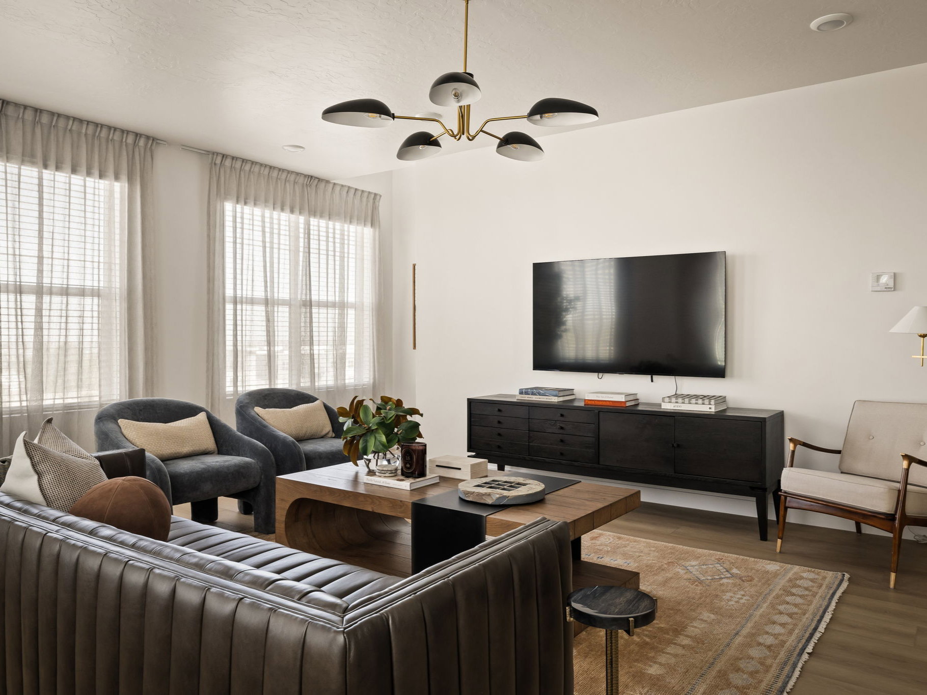 Living area featuring wood-finish flooring, white walls, and a contemporary chandelier