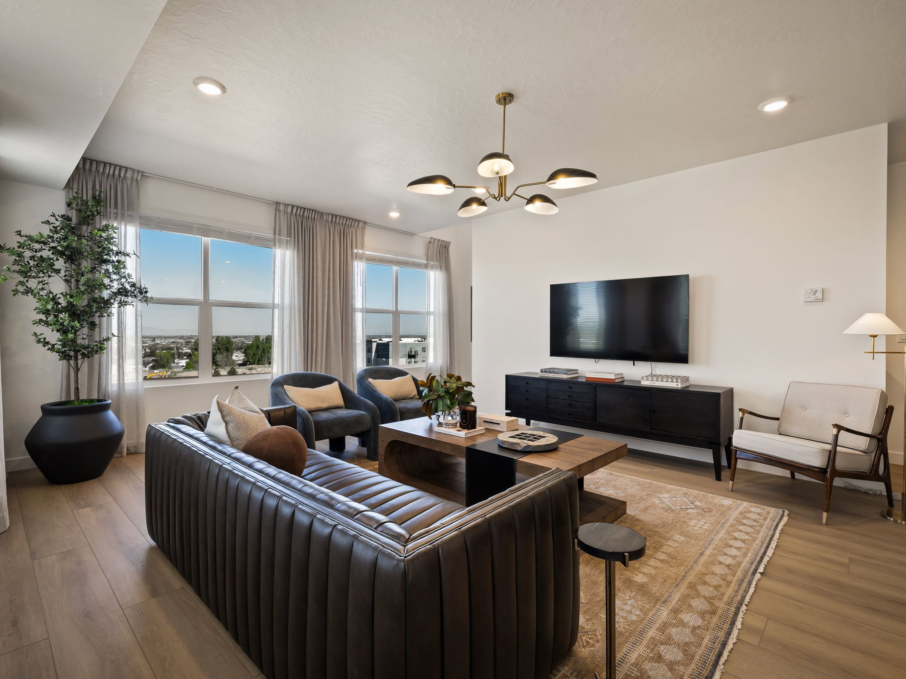 Spacious living area featuring large windows, wood-finish flooring, recessed lighting, and a modern ceiling fixture