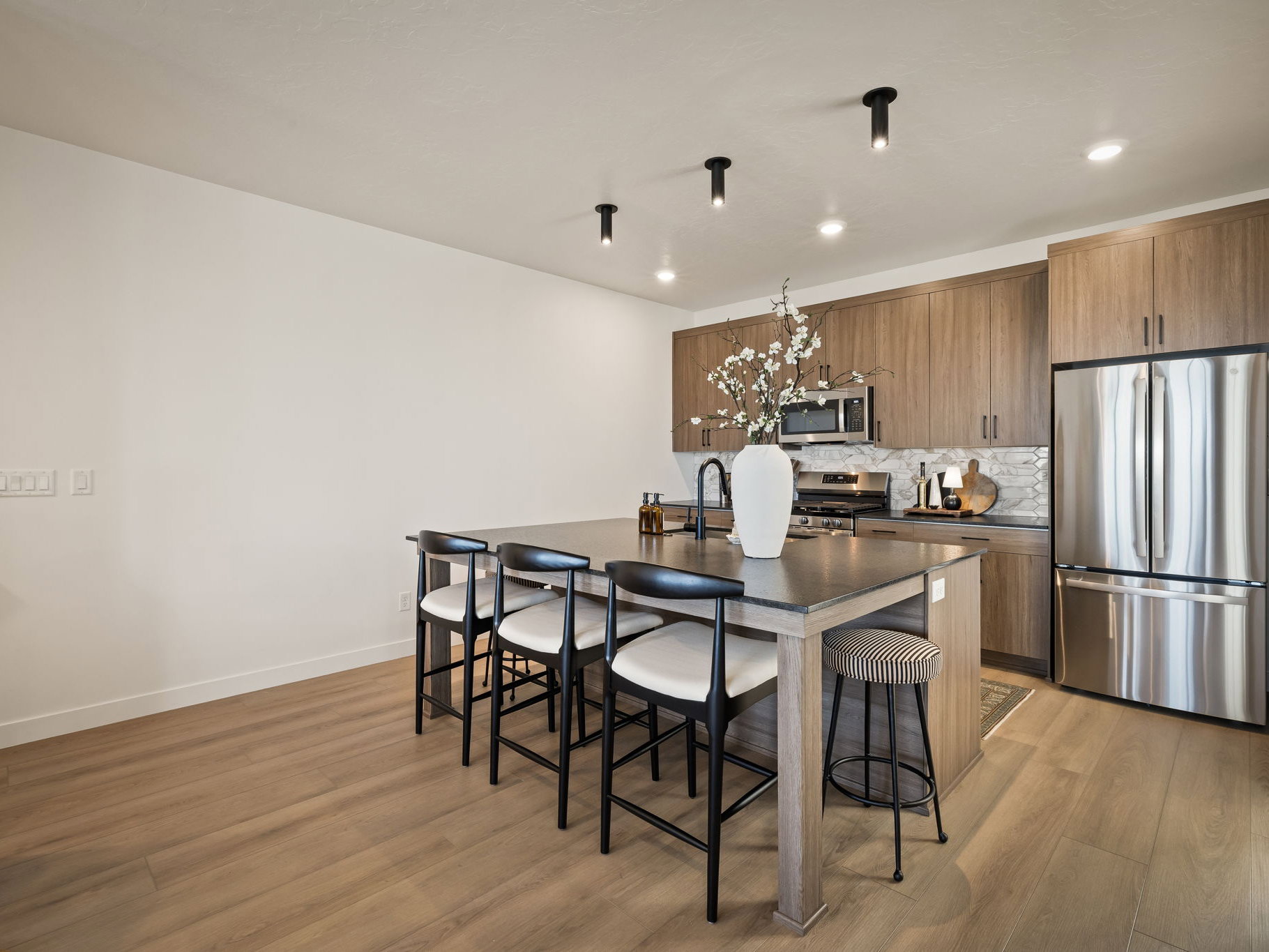 Modern kitchen featuring wood-finish flooring, a central island with seating, stainless steel appliances, wood cabinetry, and recessed lighting