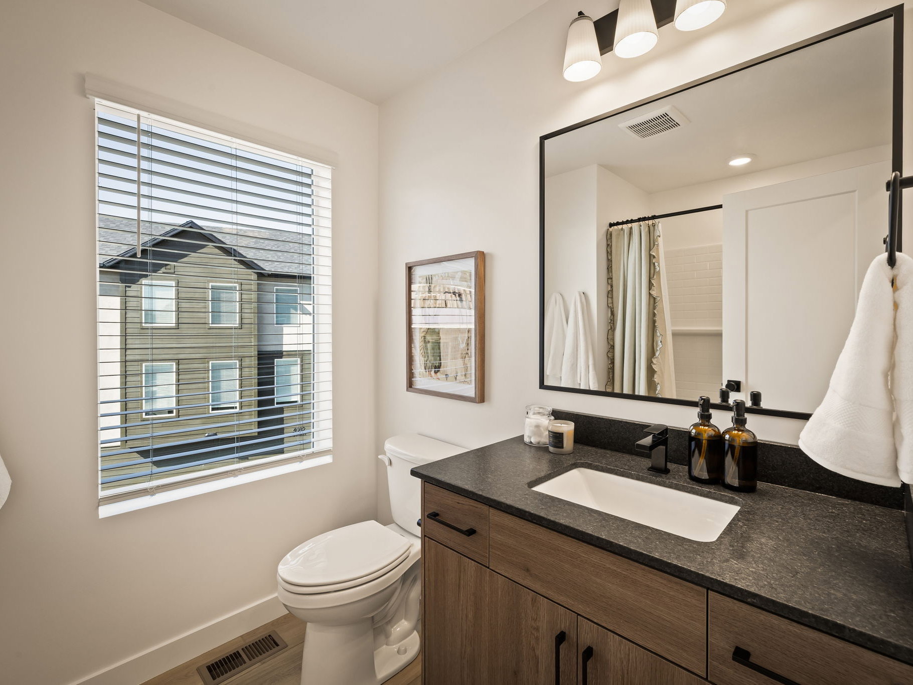 Bathroom with a wood-finish vanity and dark countertop