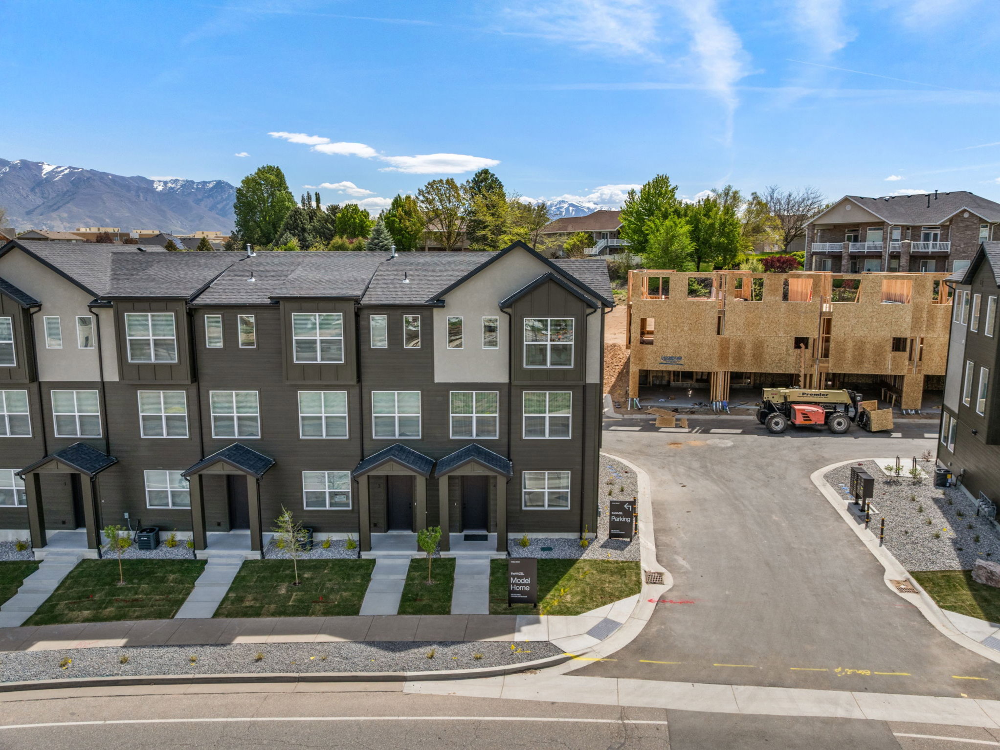 Modern townhome exterior with dark siding and light trim, featuring multiple windows and individual covered entryways