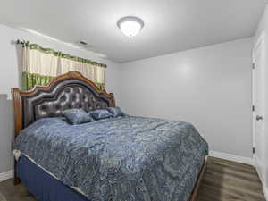 Bedroom featuring wood-finish flooring and a white paneled door with a brushed nickel knob