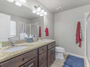 Double vanity featuring a granite-finish countertop, under-mount sinks, and dark wood cabinetry