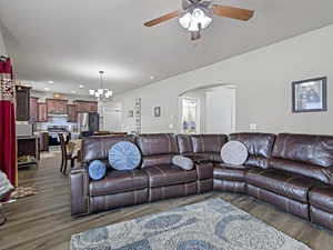 Open-concept living area with wood-finish flooring, a ceiling fan, and an arched doorway