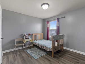 Bright room featuring wood-finish flooring, a white trim baseboard, a window with horizontal blinds, and a flush-mount ceiling light fixture