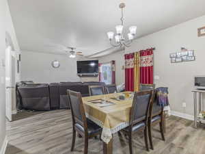 Dining area featuring wood-finish flooring, a multi-light chandelier, and an open archway to the living space