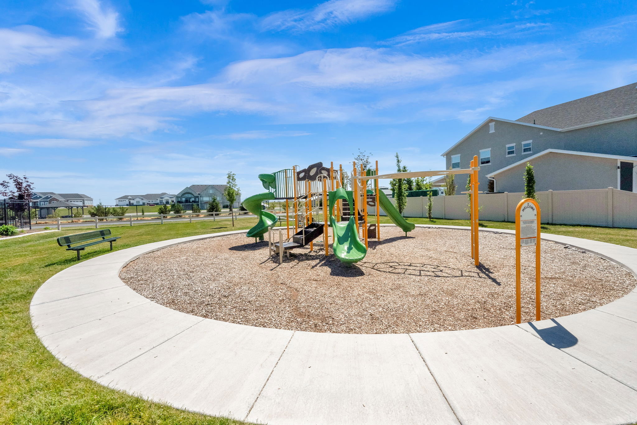 Community playground featuring green slides, yellow support structures, and a wood chip surface