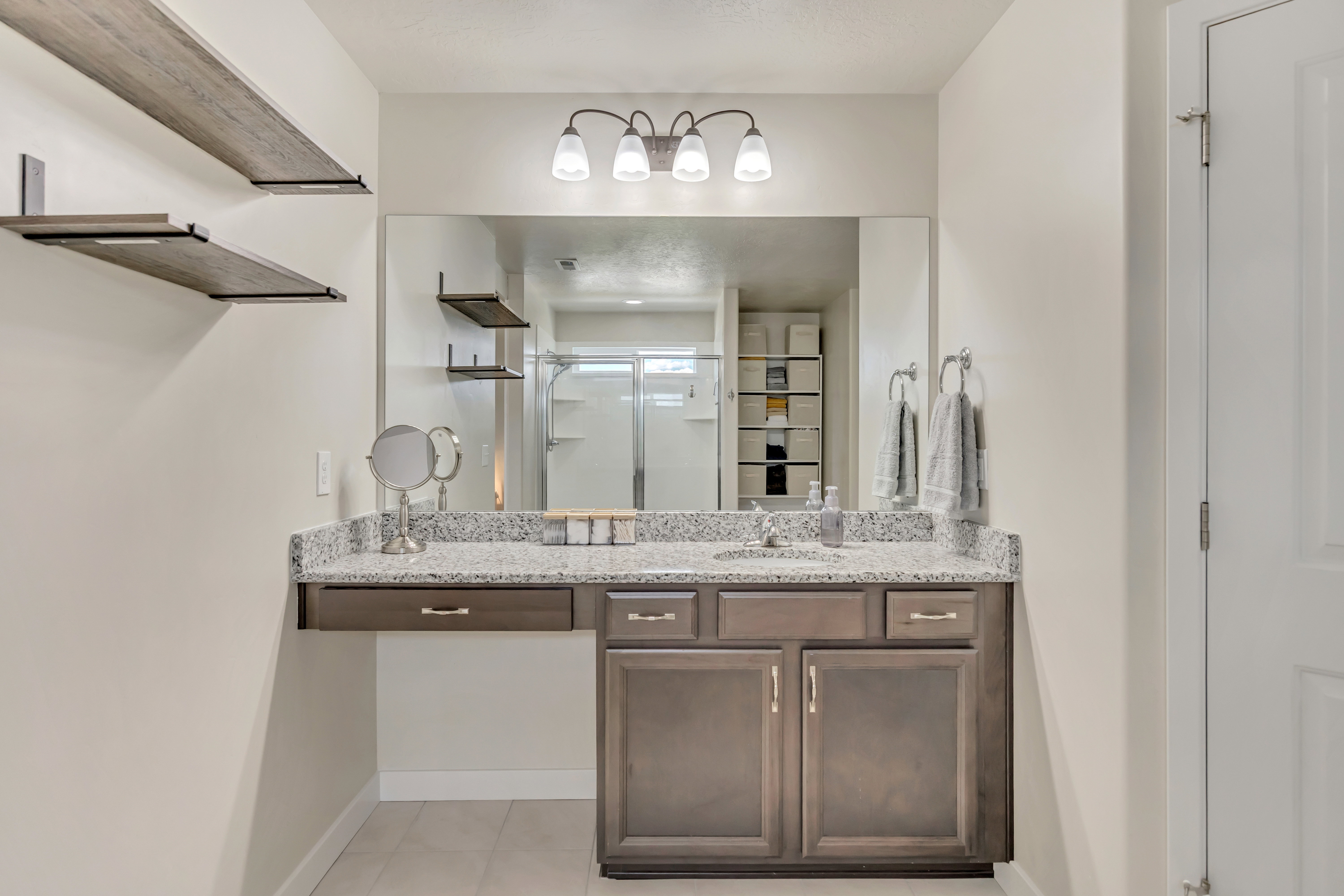 Vanity area featuring a spacious countertop with an integrated sink, dark wood-finish cabinetry, and a large wall-mounted mirror