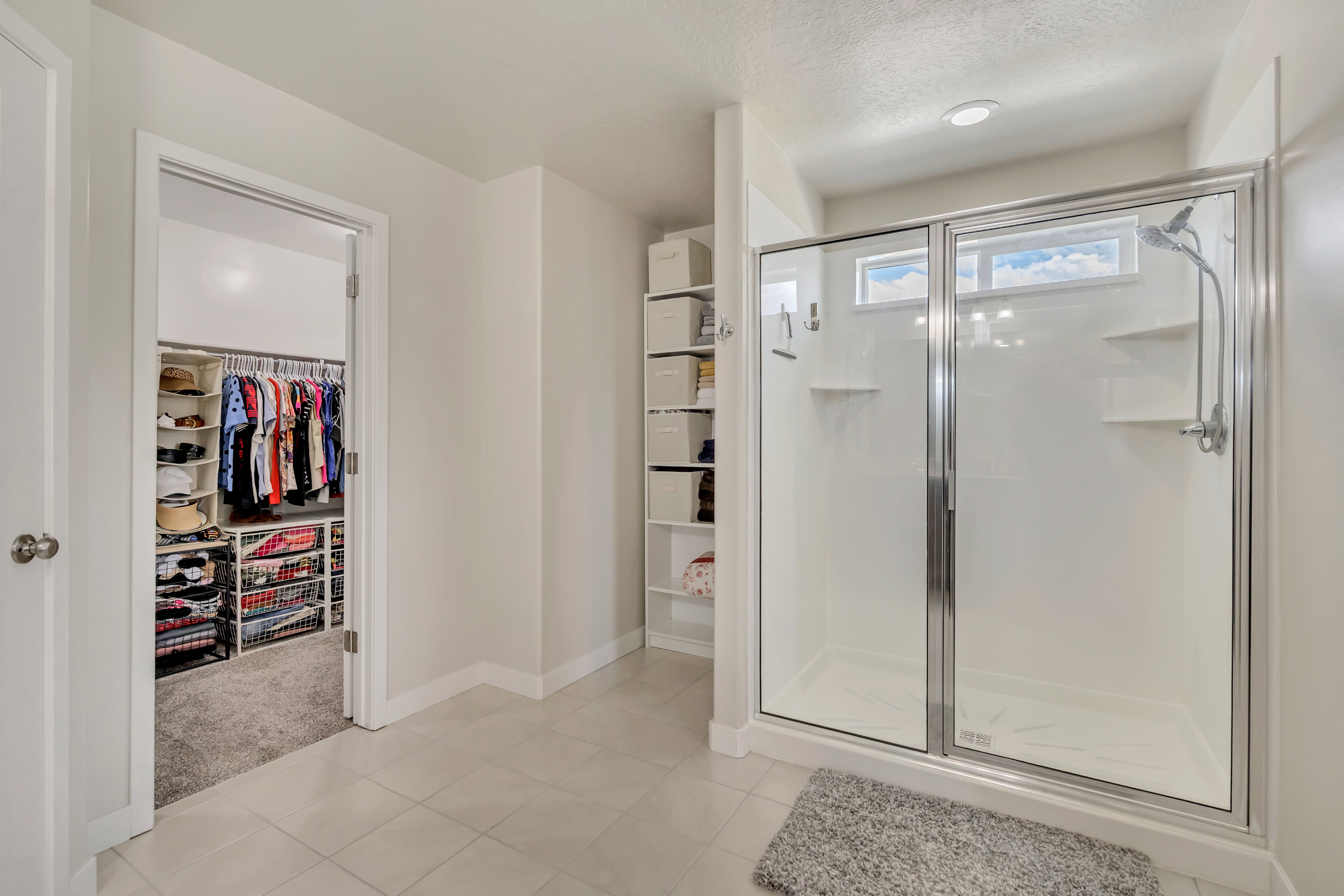 Glass-enclosed shower with transom window and wall-mounted shelving