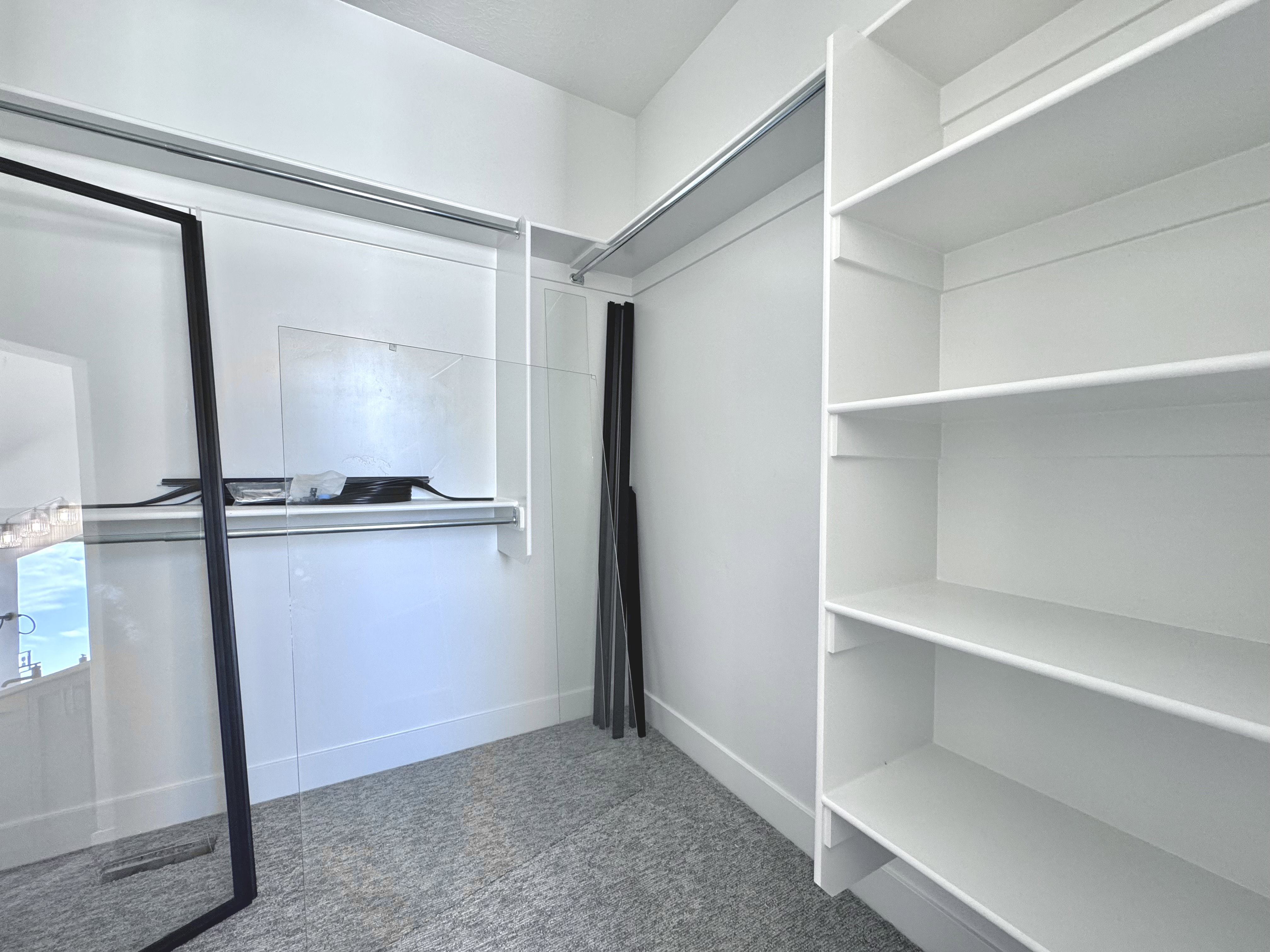 Walk-in closet featuring built-in shelving, hanging rods, and light gray carpeting