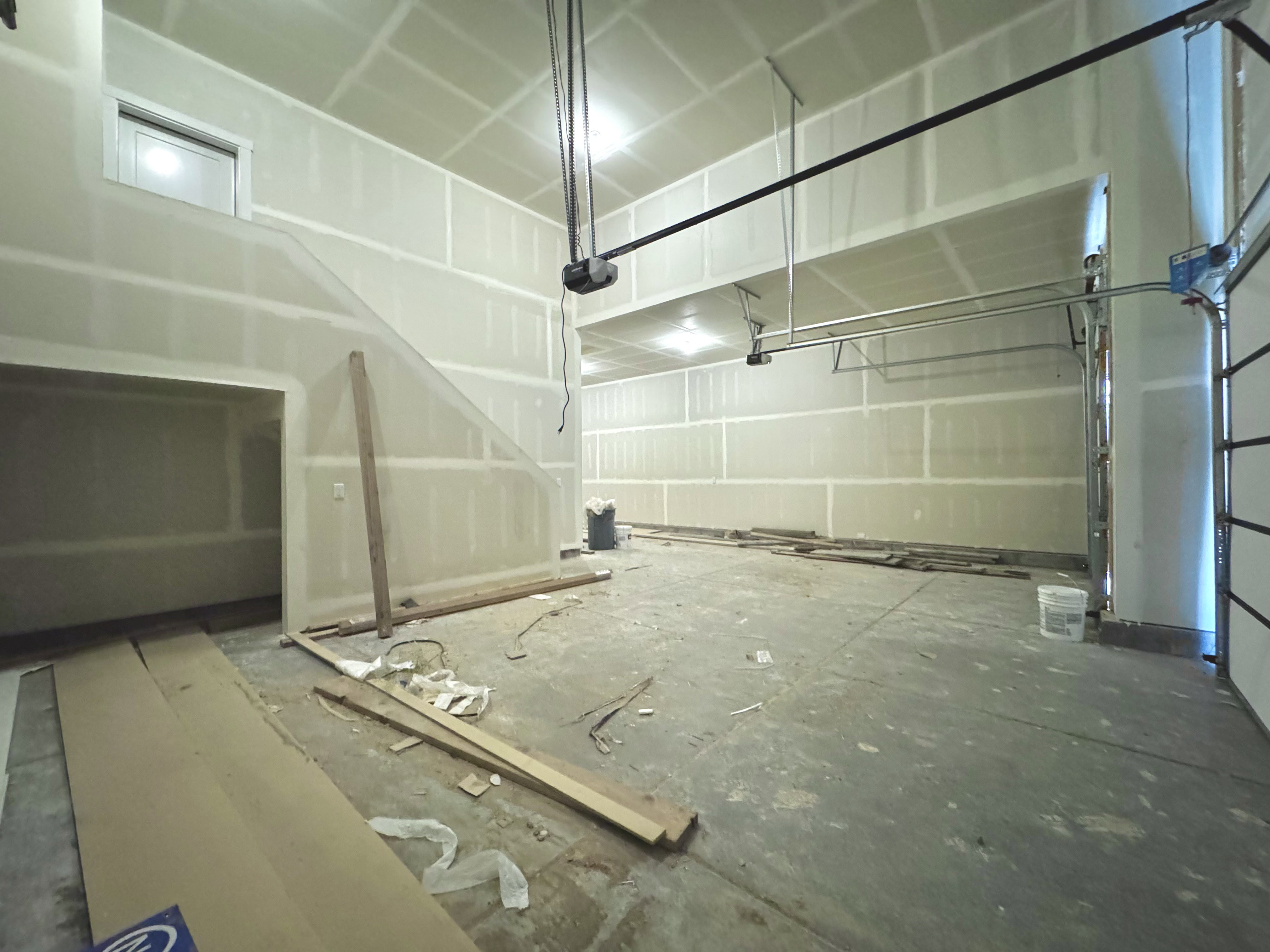 Spacious unfinished interior featuring high ceilings, exposed structural elements, and a visible garage door mechanism