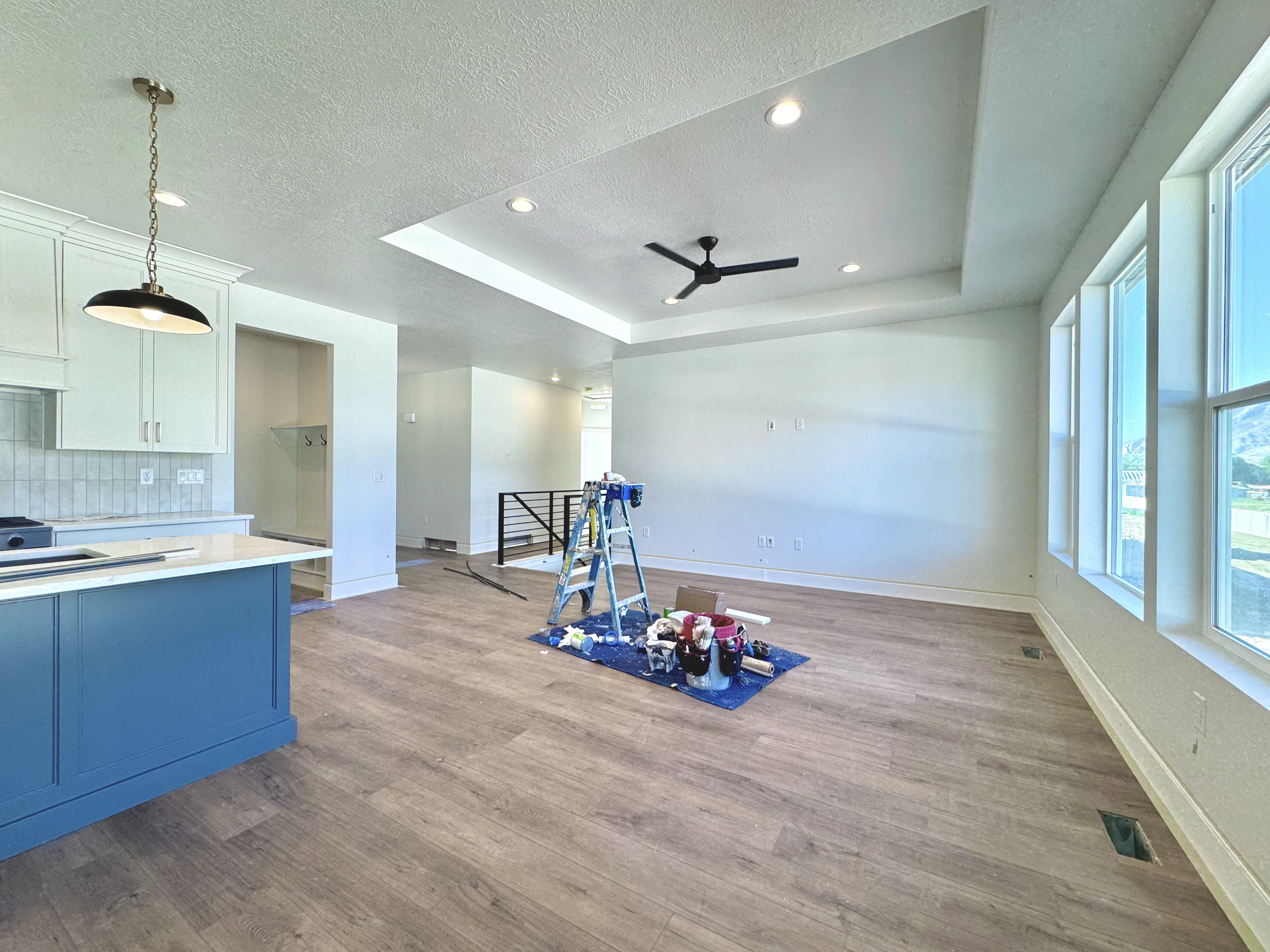 Spacious open-concept living area featuring wood-finish flooring and a tray ceiling with recessed lighting