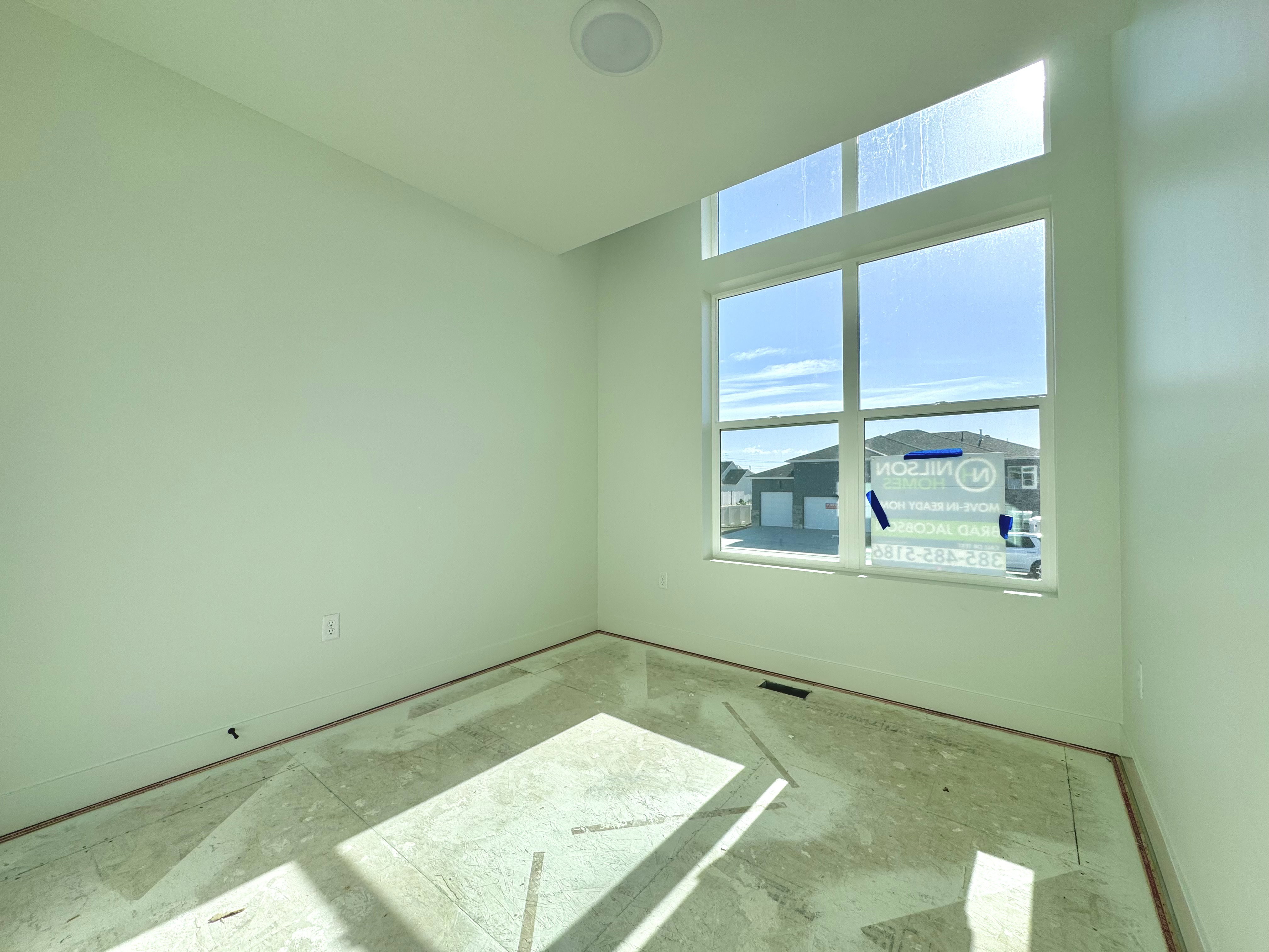 Room featuring a large window with transom, light green painted walls, white trim, and a ceiling-mounted light fixture