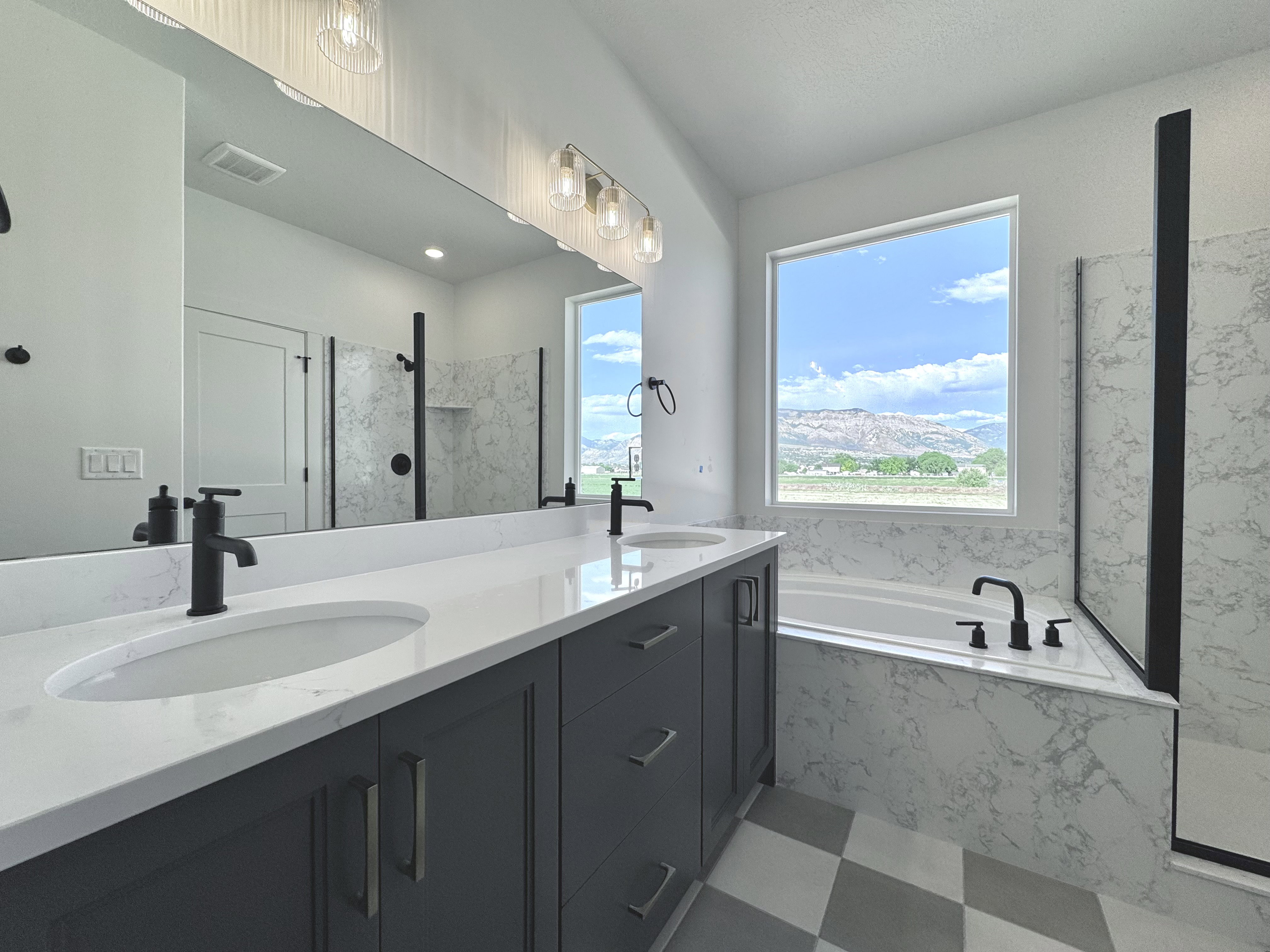 Bathroom featuring a double vanity with white countertops, dual undermount sinks, and matte black fixtures
