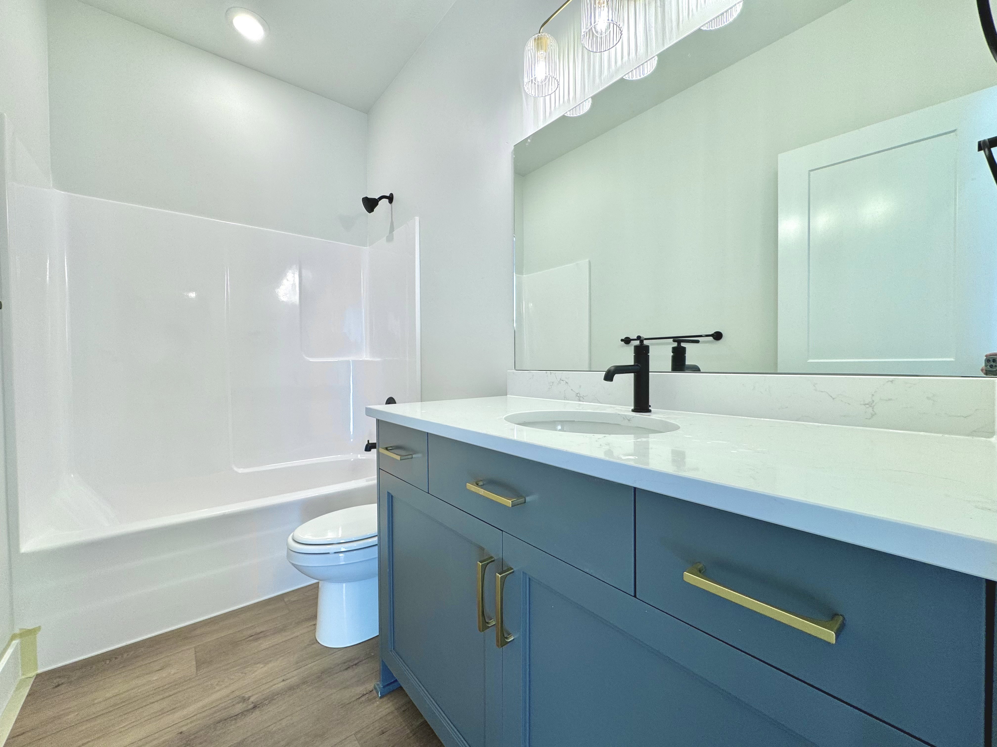 Bathroom featuring a blue vanity with gold hardware, a white countertop, and an undermount sink with a matte black faucet