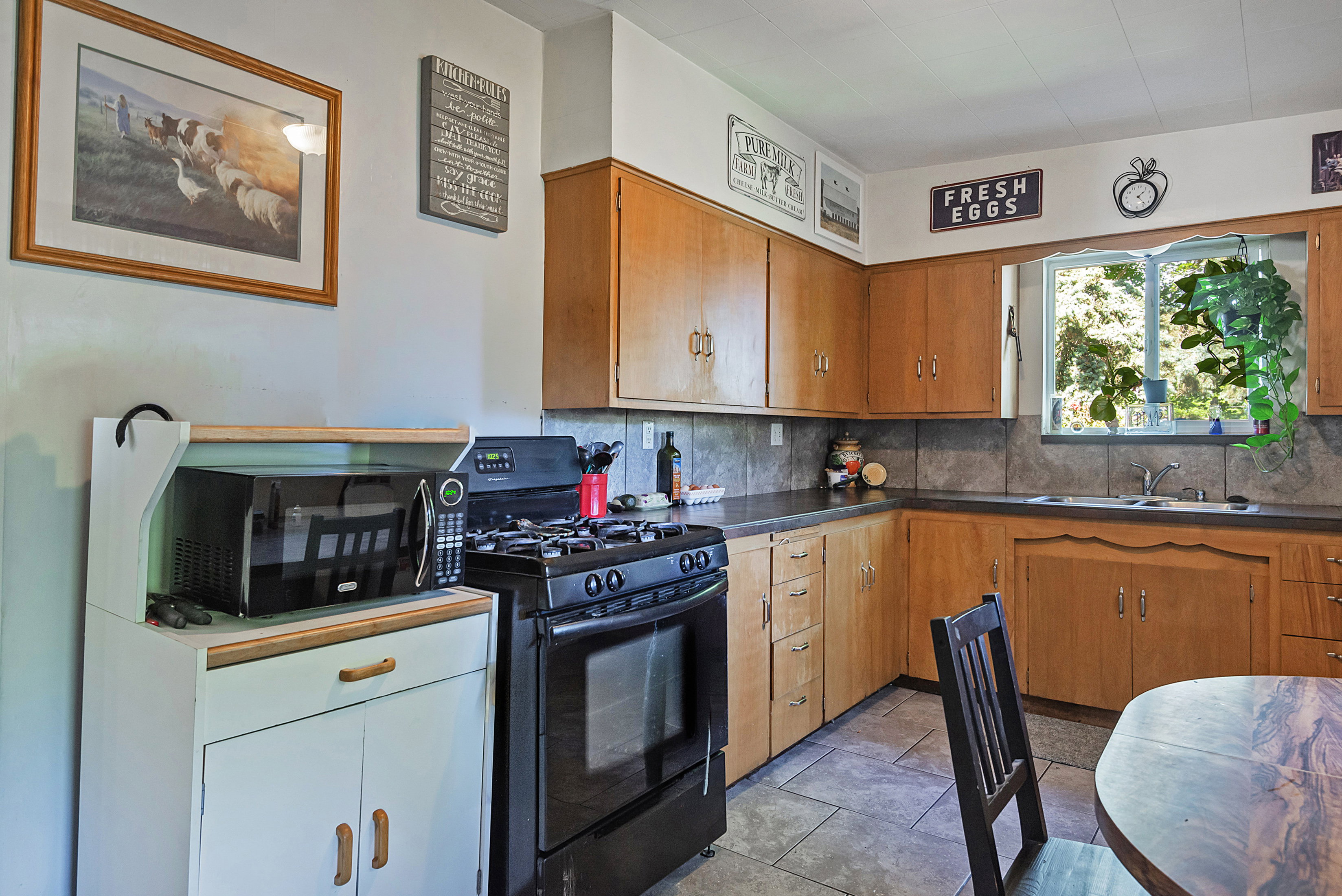Kitchen featuring wood cabinetry, dark countertops, a tile backsplash, and tile flooring