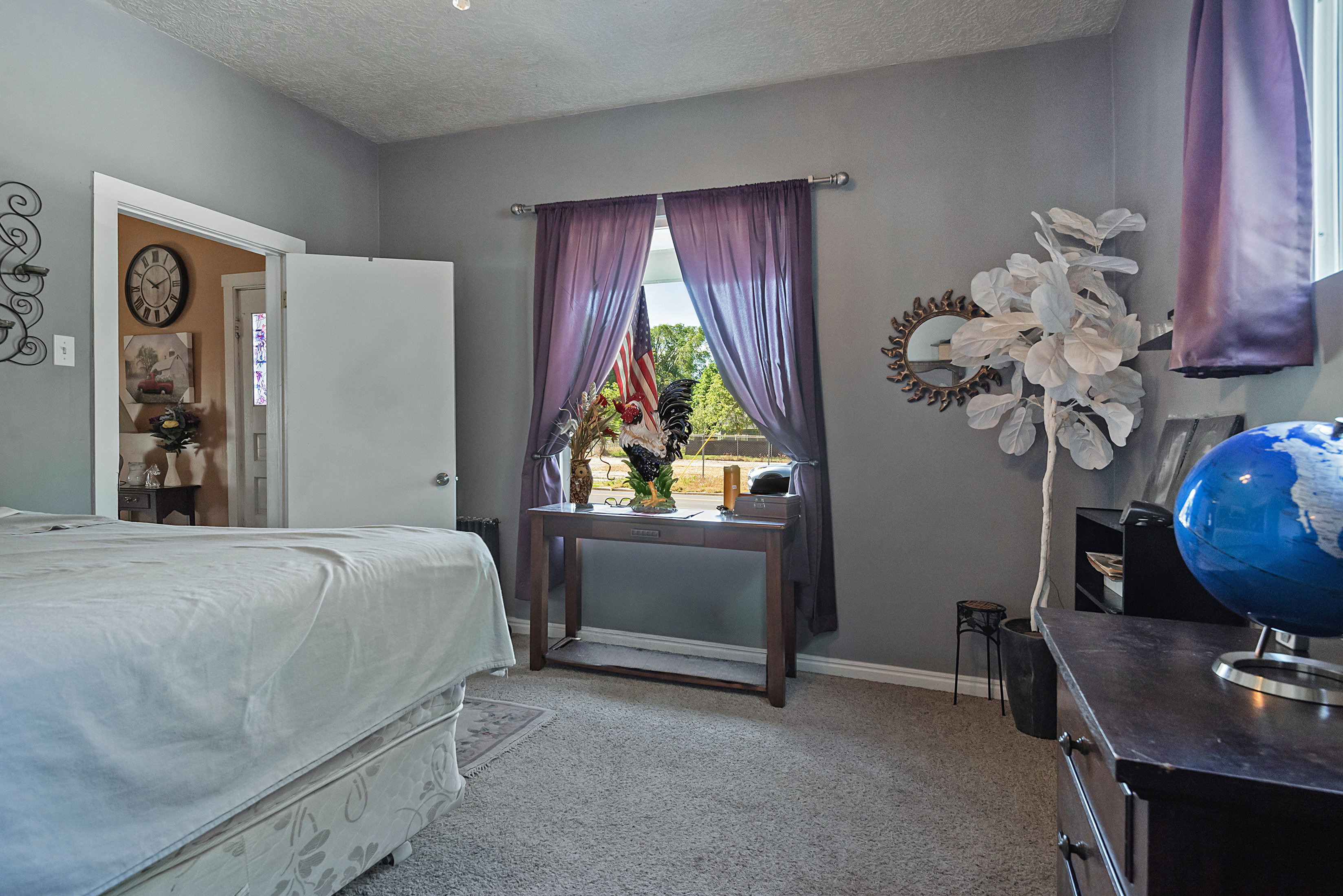 Carpeted room featuring a window with purple drapes, a white paneled door, and gray wall paint