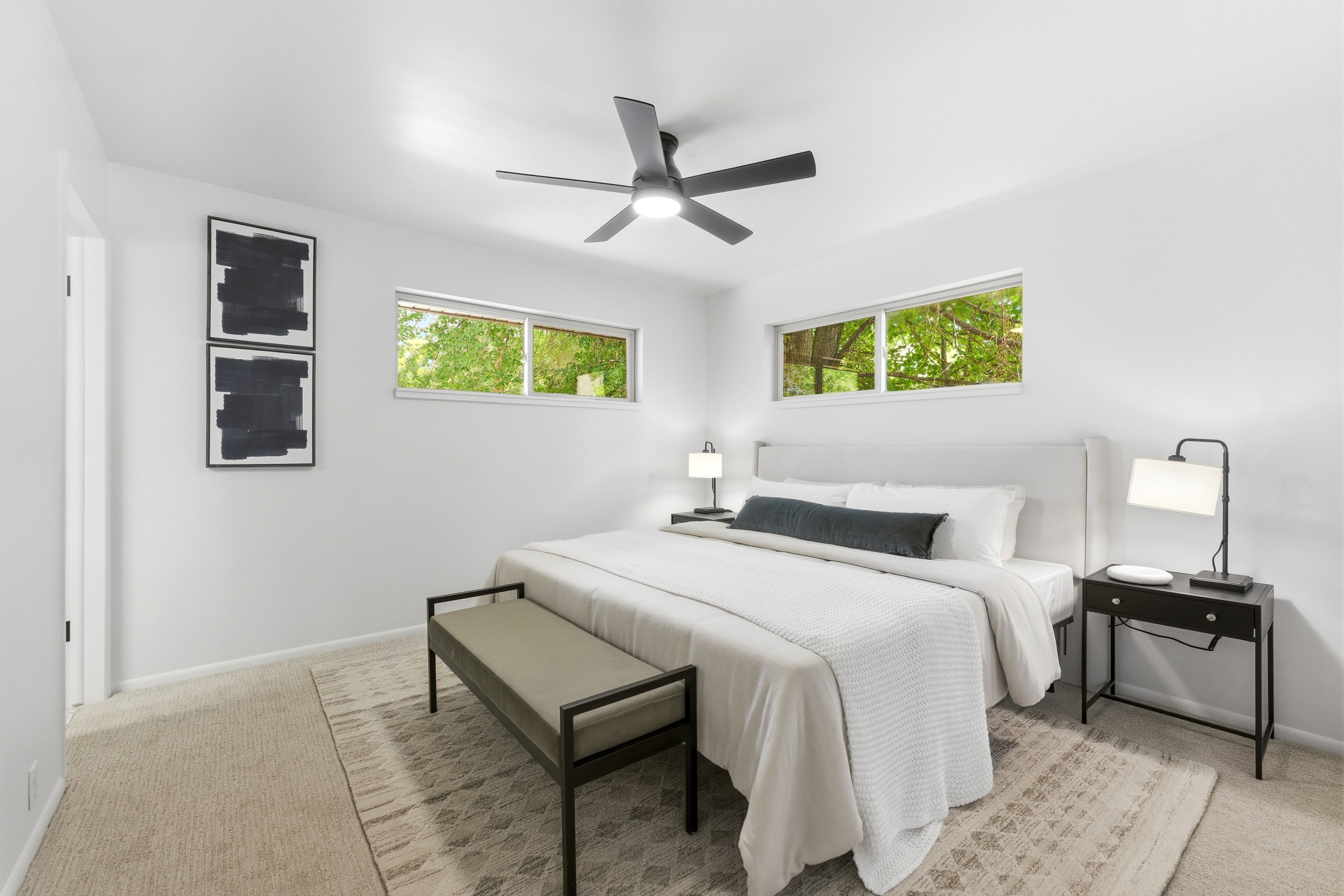 Bright bedroom featuring two transom windows, a ceiling fan, and light-colored carpeting