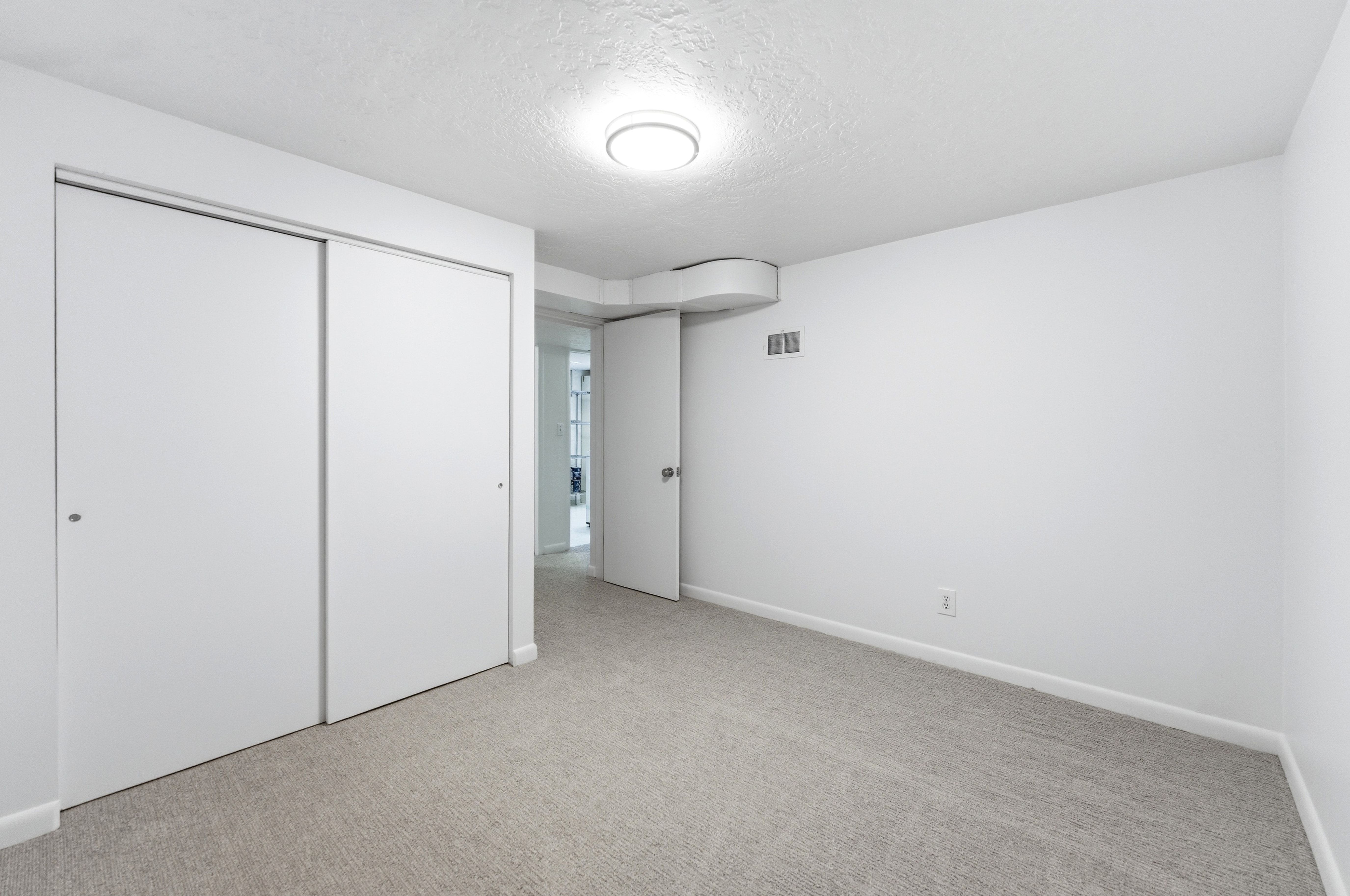 Carpeted interior room featuring white walls, white baseboards, and a flush mount ceiling light fixture