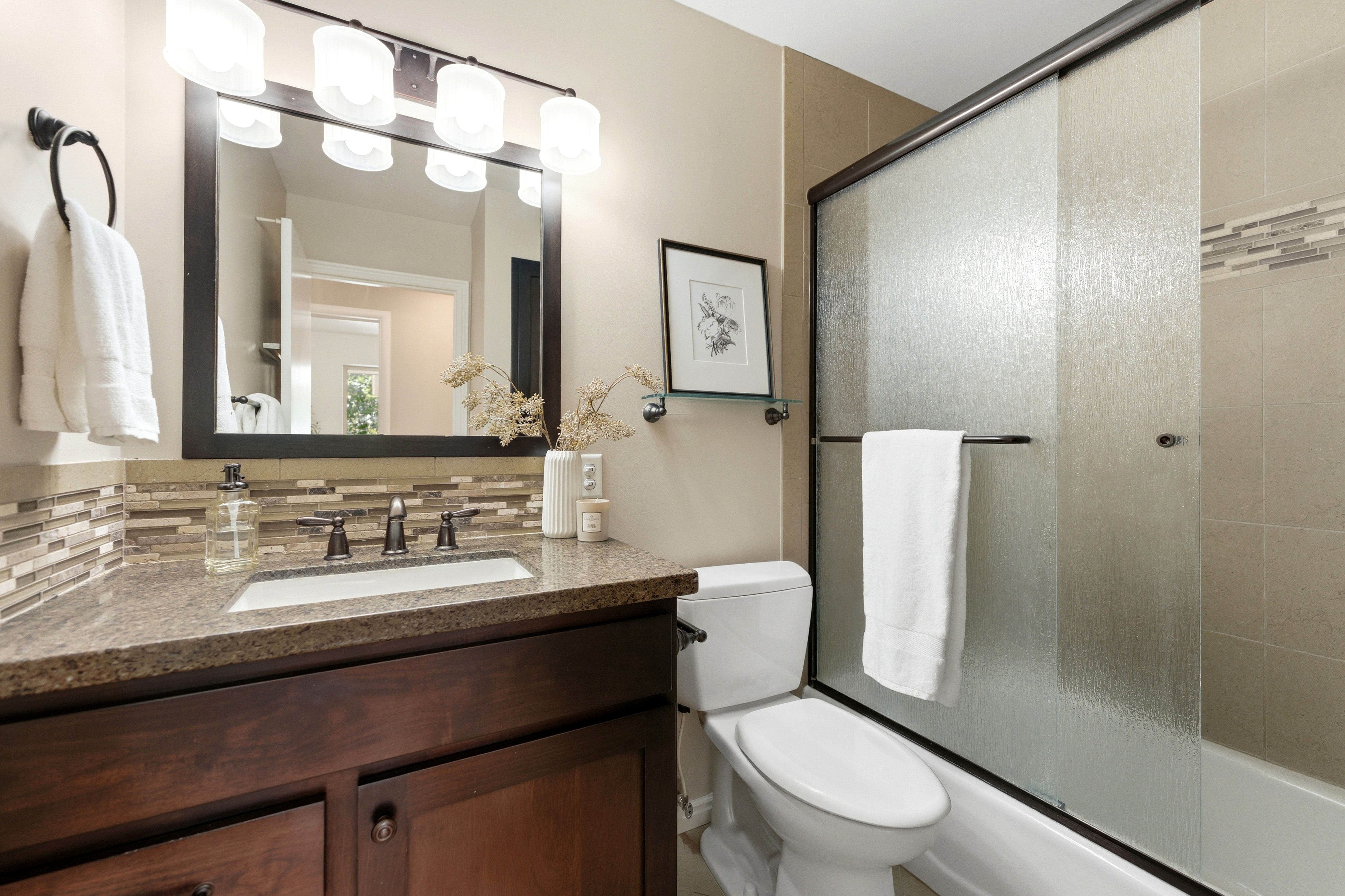 Vanity with a granite-style countertop, undermount sink, and dark wood cabinetry