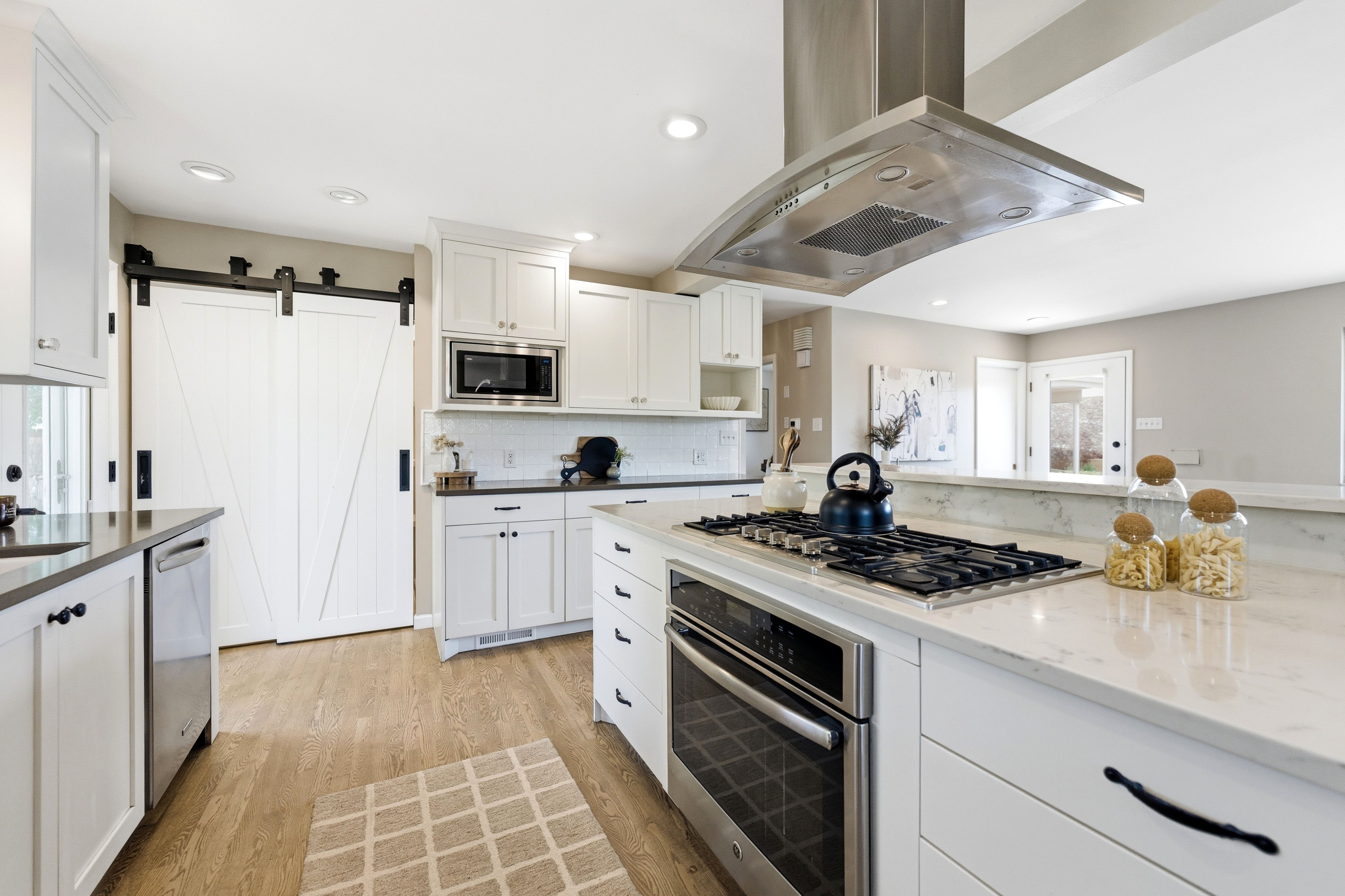 Gourmet kitchen featuring a central island with a gas cooktop, built-in oven, and a stainless steel range hood