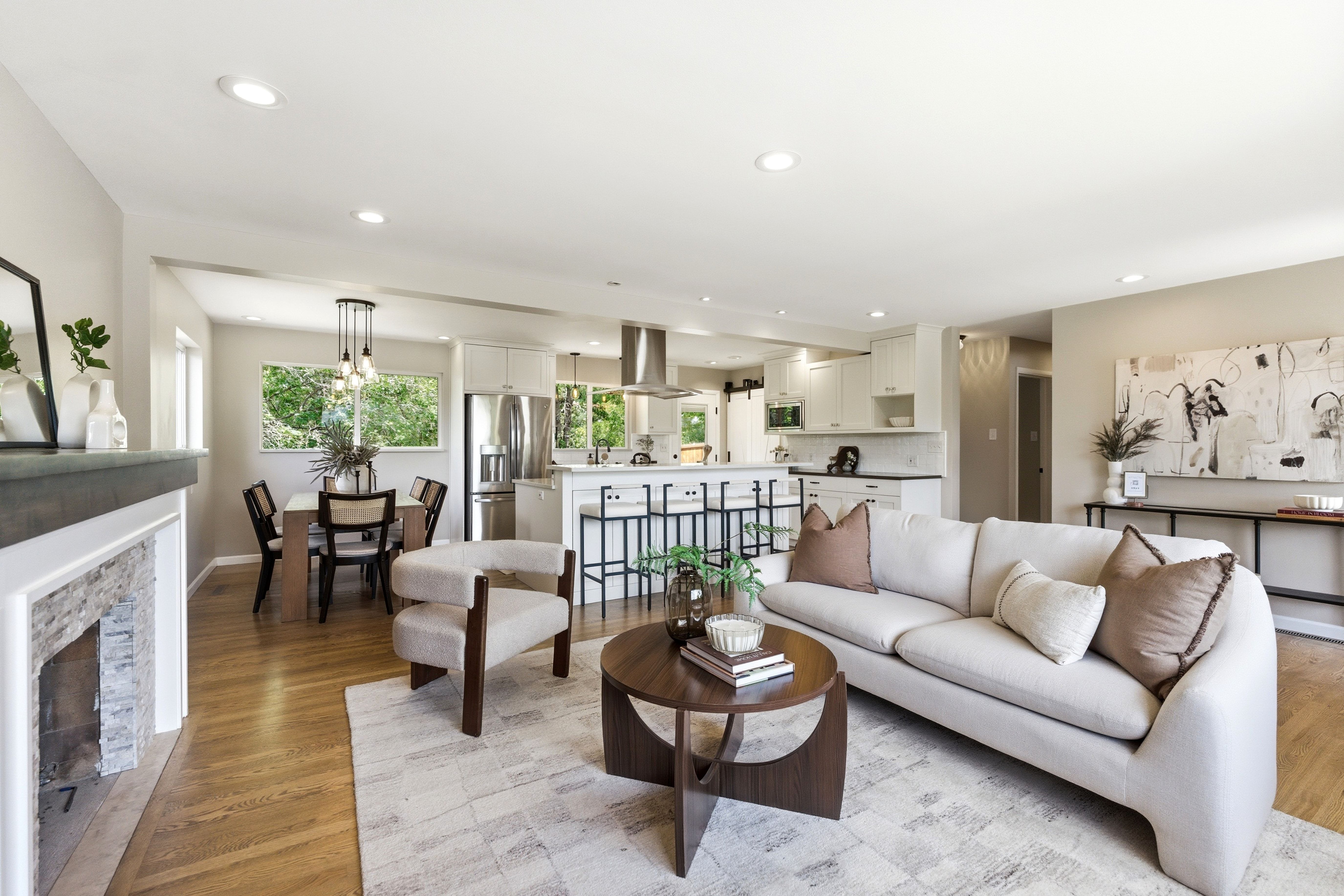 Open-concept living space featuring wood-finish flooring, recessed lighting, and a stone-clad fireplace