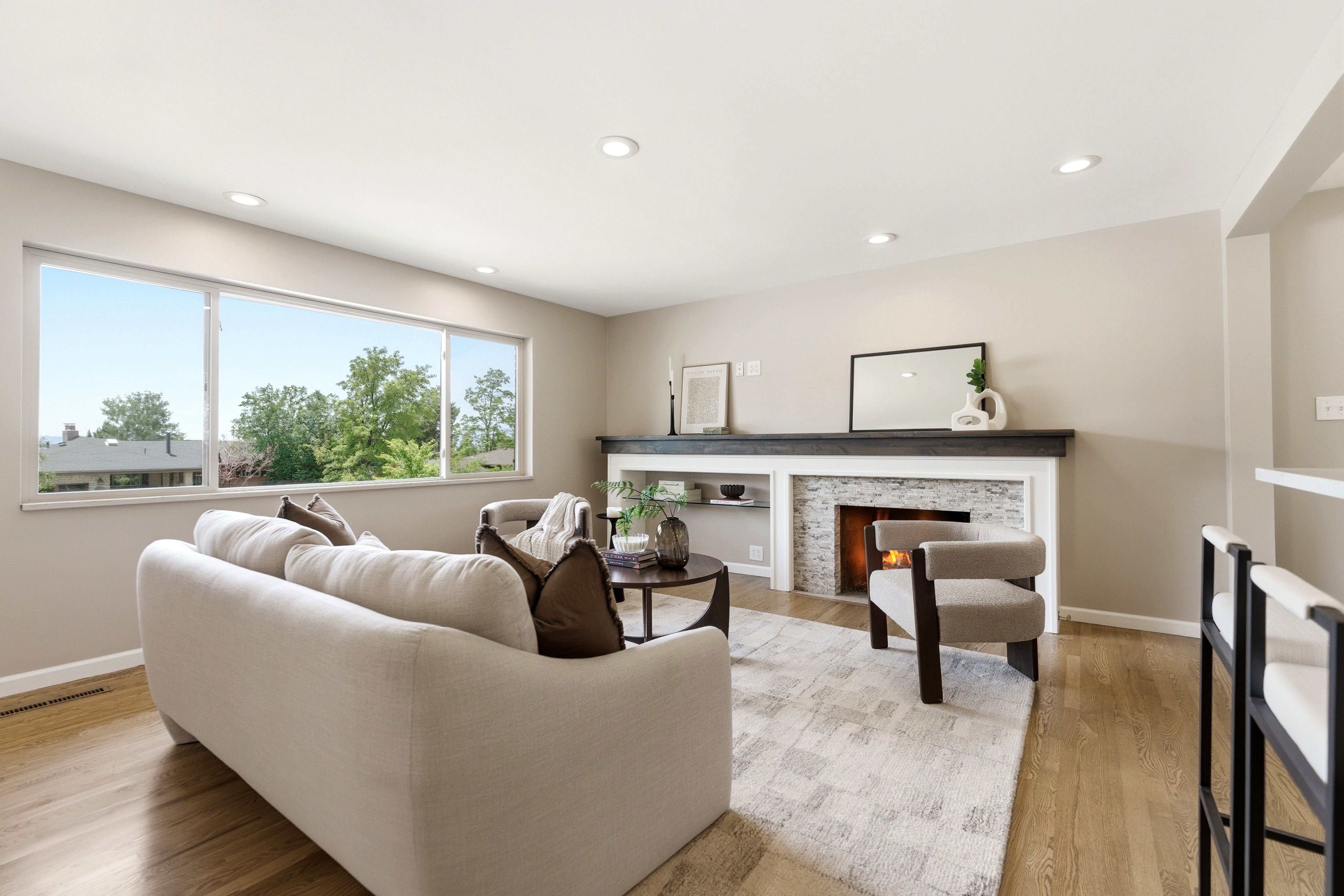 Spacious living room featuring wood-finish flooring, recessed lighting, and a stacked stone fireplace with a dark wood mantel
